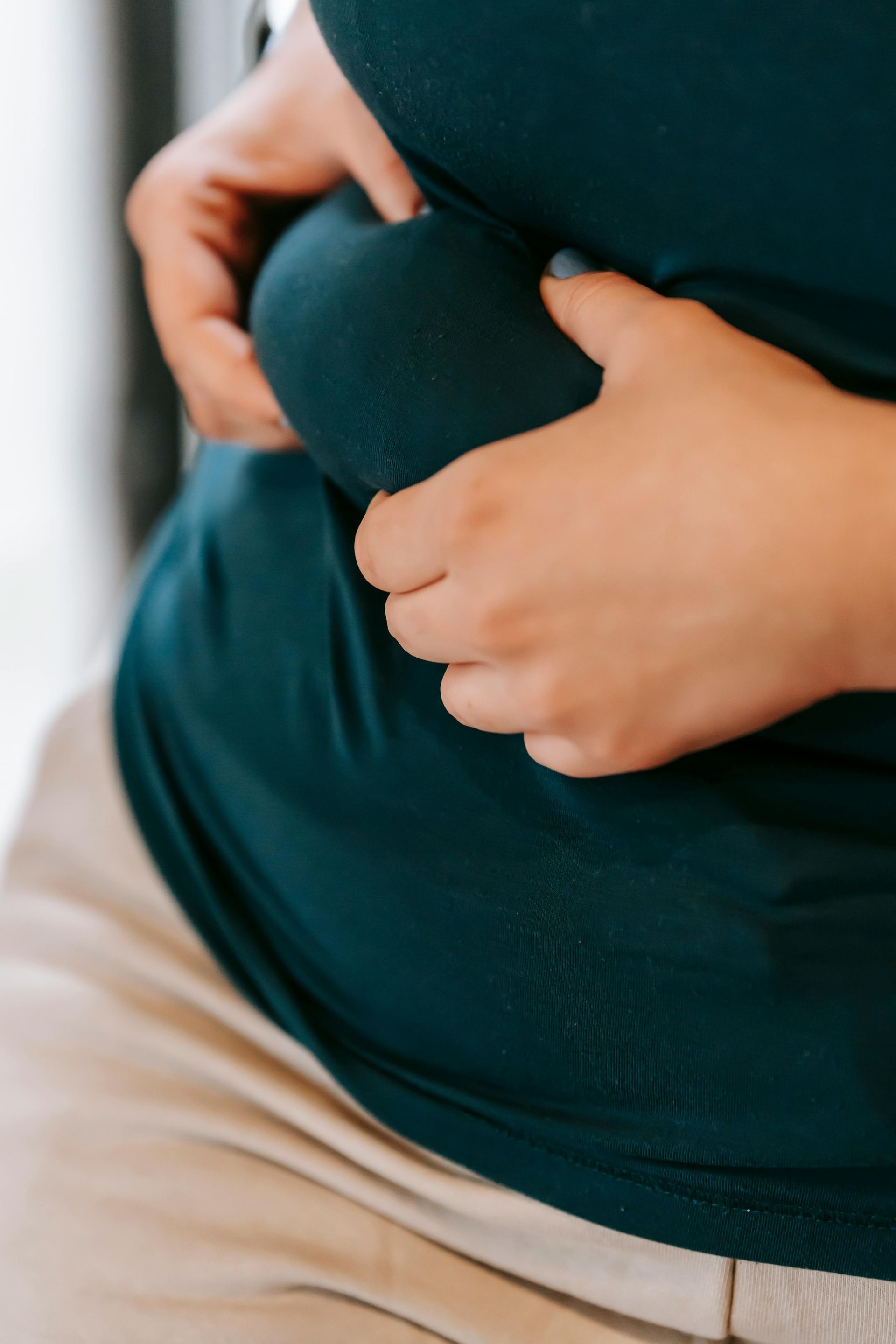 Person in dark shirt holding their belly, a sign of possible weight gain.