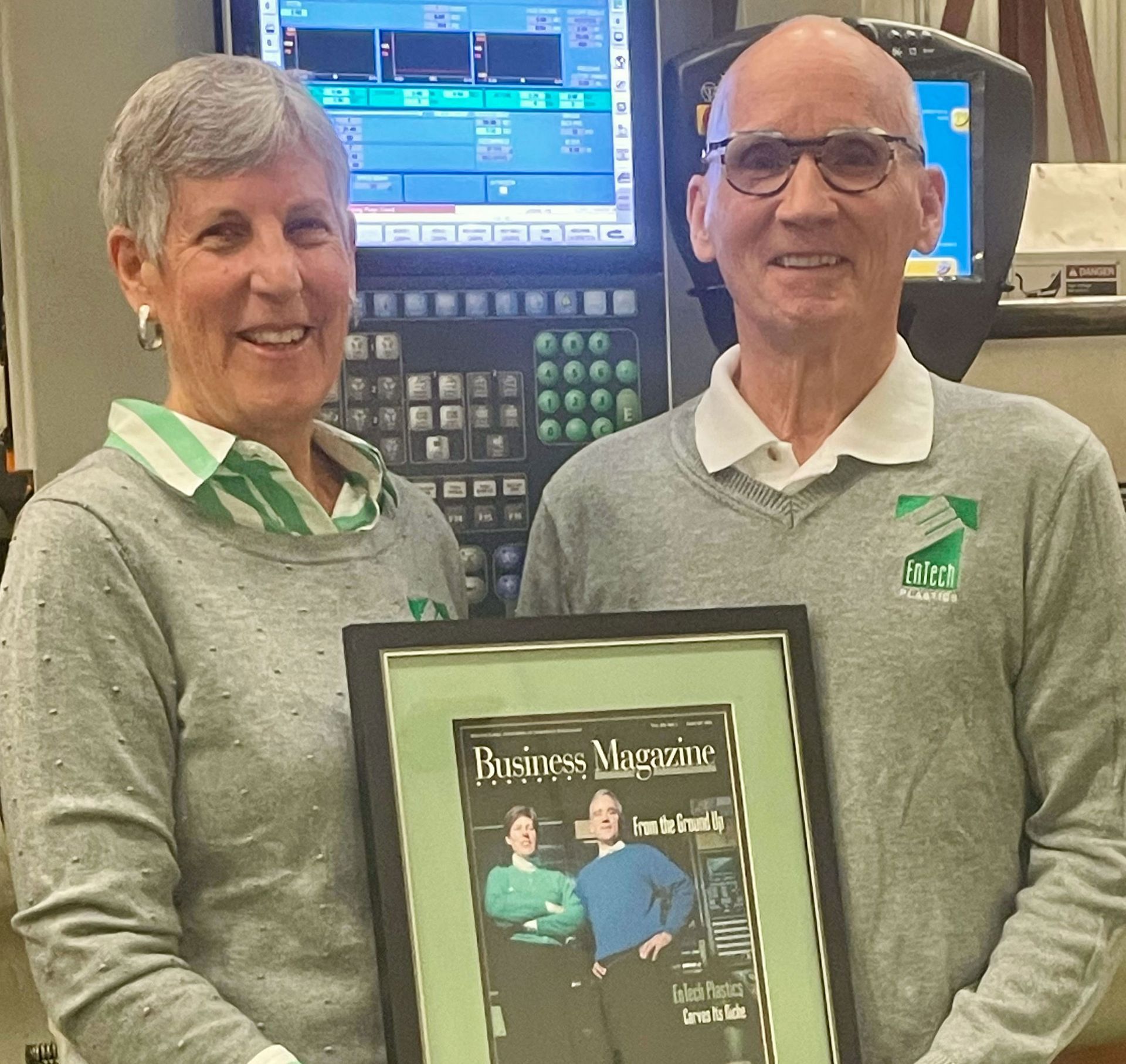 Sally and Kevin Gearity posed together holding a framed Business Magazine cover