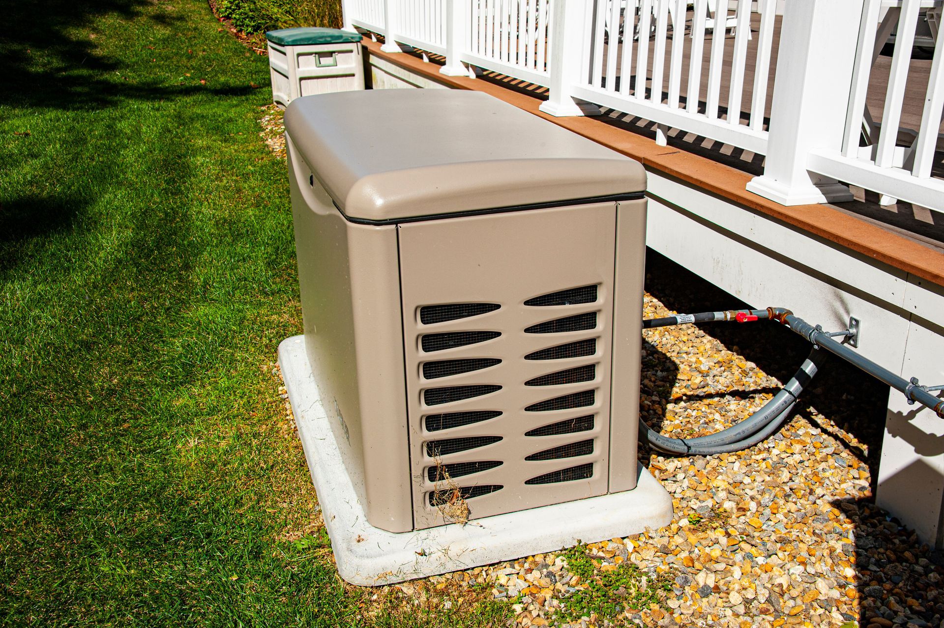 Outdoor whole-home standby generator installed on a concrete pad beside a deck