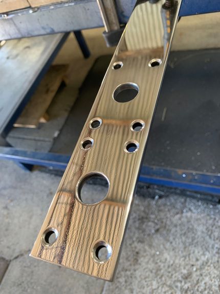 Perforated wooden strip with multiple drilled holes, resting on a workbench. — Jensen Welding & Fabrication in Chevallum, QLD