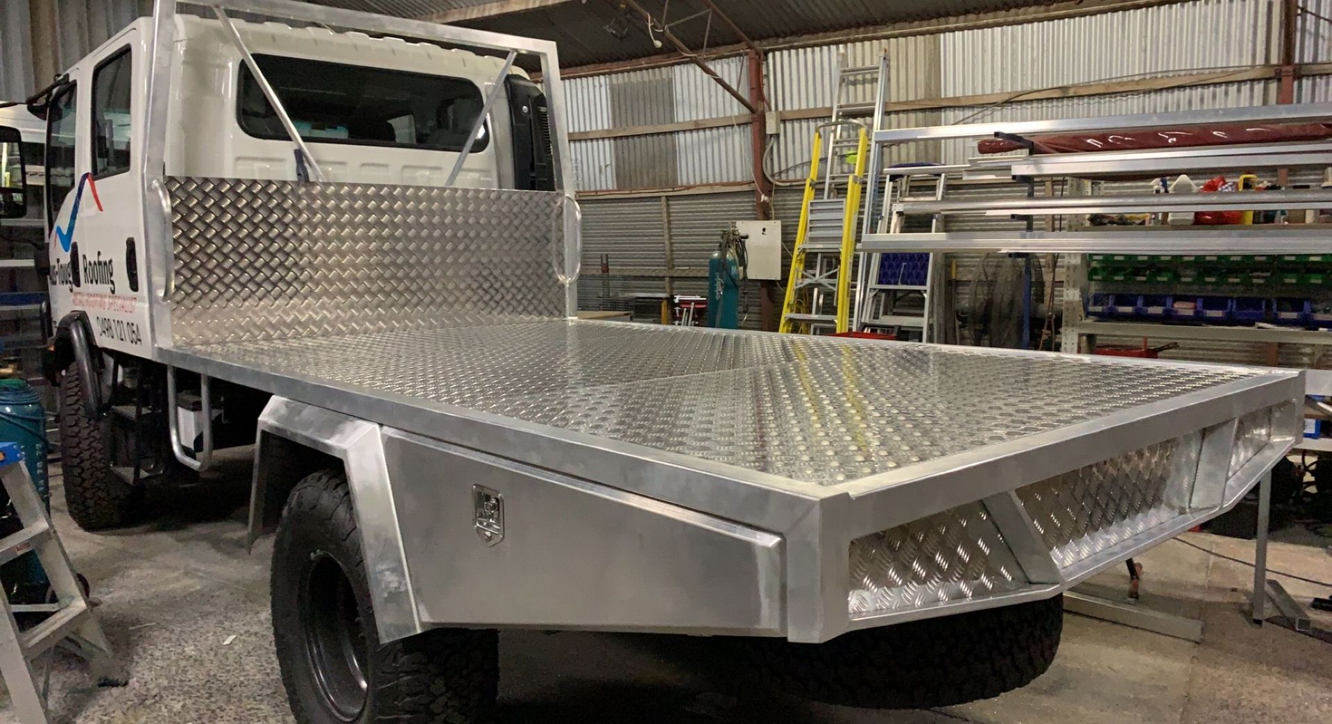 Silver flatbed truck with diamond-plate body parked inside a workshop  — Jensen Welding & Fabrication in Chevallum, QLD