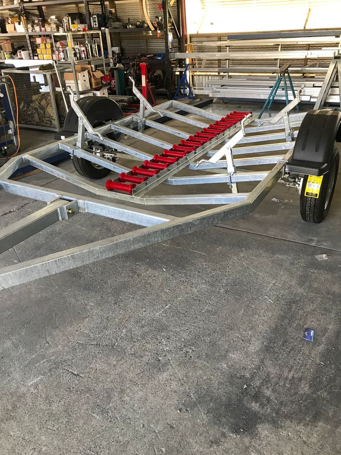 Silver boat trailer with red roller bunks in a garage or workshop — Jensen Welding & Fabrication in Chevallum, QLD