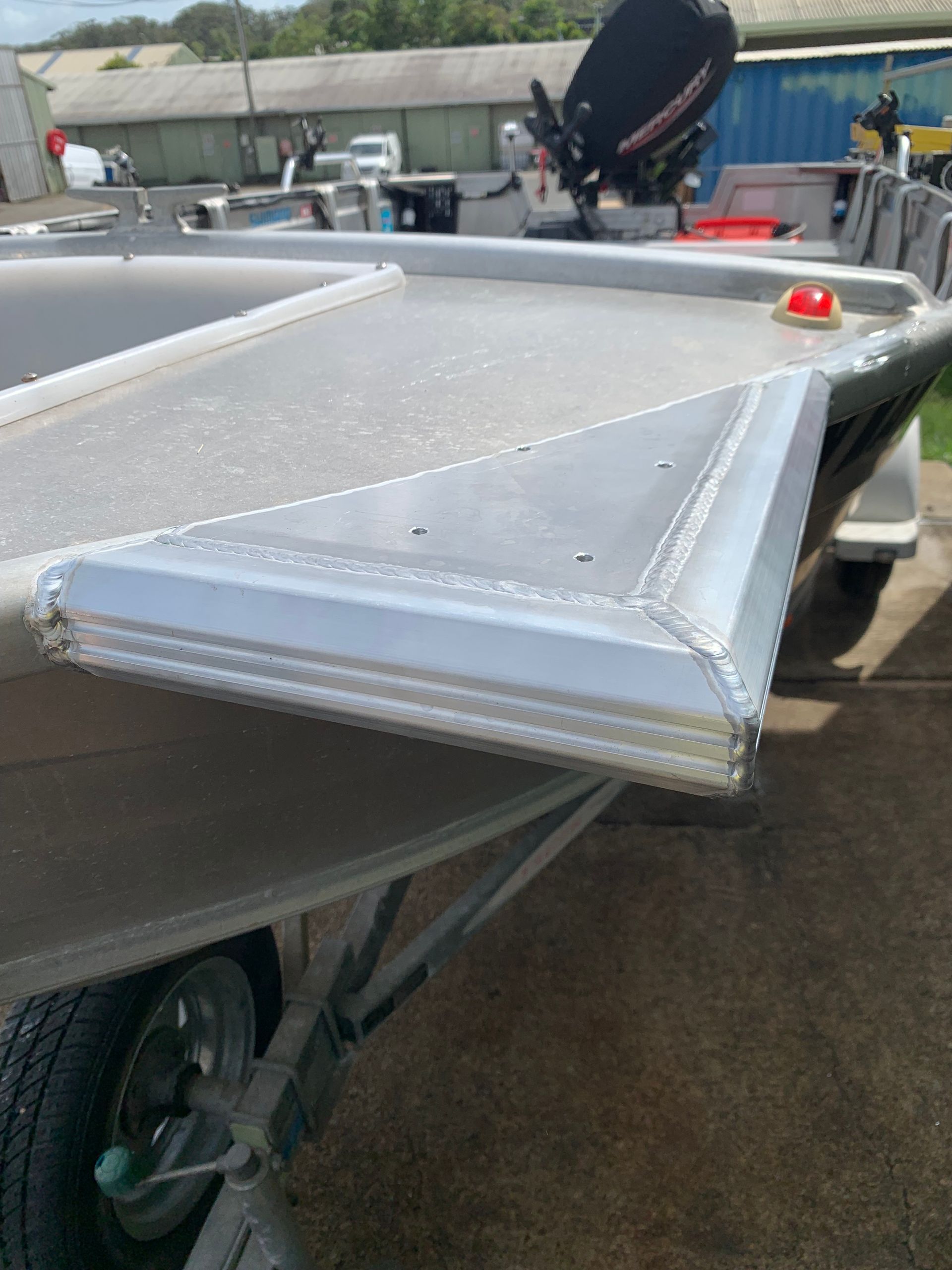 Aluminum boat trailer with a wet deck and red marker light, parked on pavement outdoors — Jensen Welding & Fabrication in Chevallum, QLD