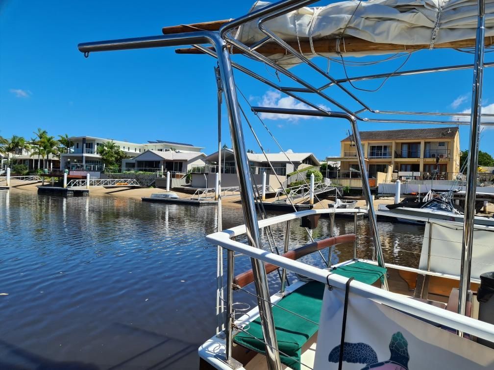 Canal marina with docked boats, covered deck in foreground, and waterfront homes under a blue sky  — Jensen Welding & Fabrication in Chevallum, QLD
