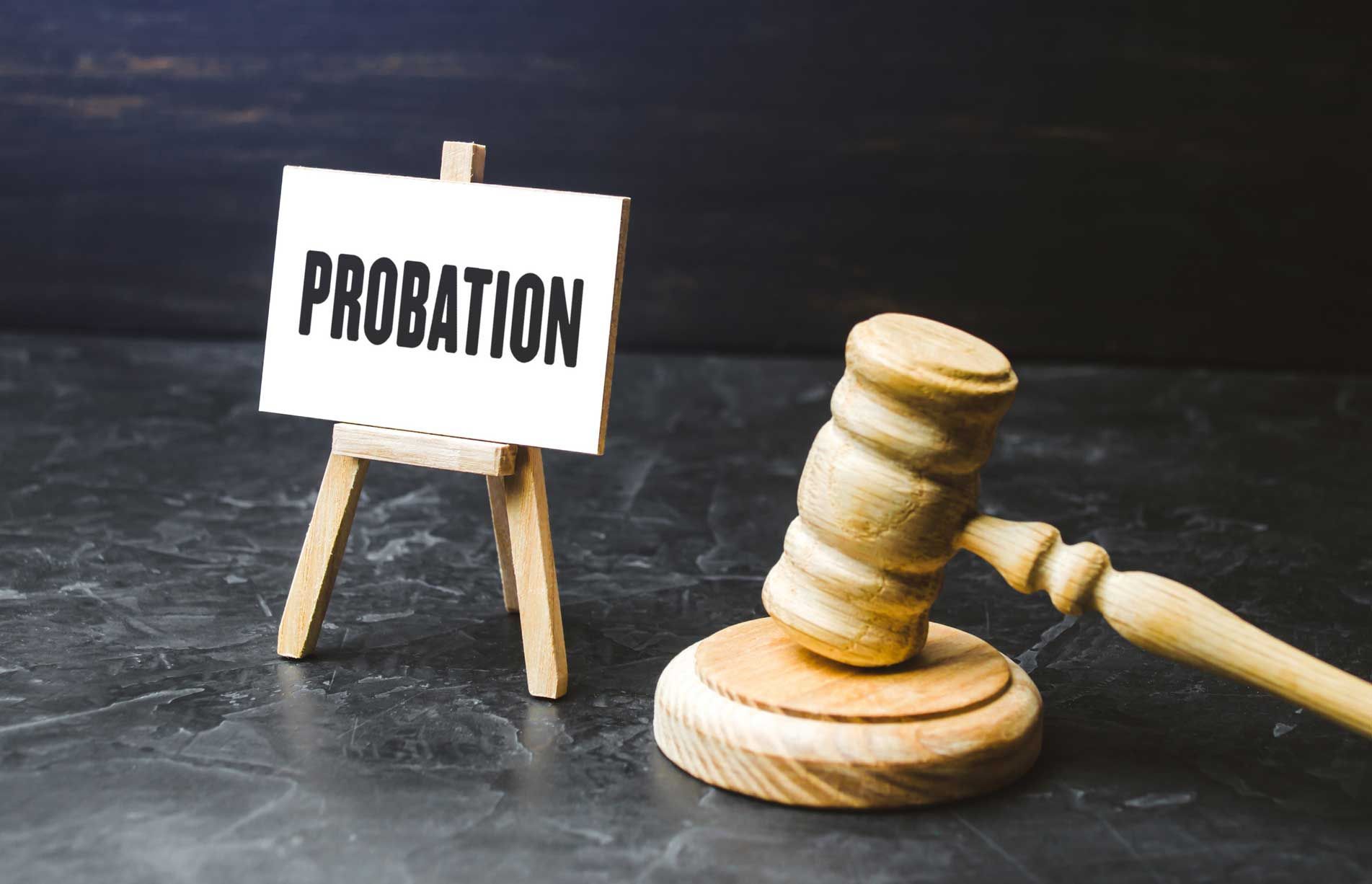 A wooden gavel is sitting next to a sign that says probation.