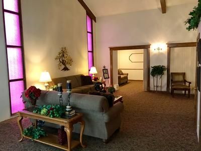 Church or chapel interior with pews, stained-glass windows, and a sofa in a quiet lounge area