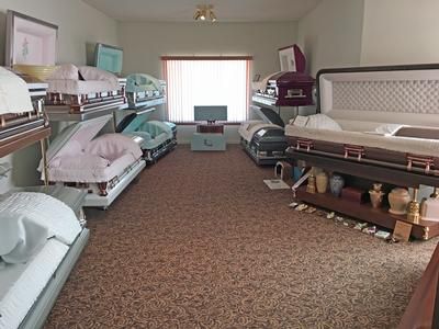 Bedroom furniture showroom with rows of beds and a large window at the back