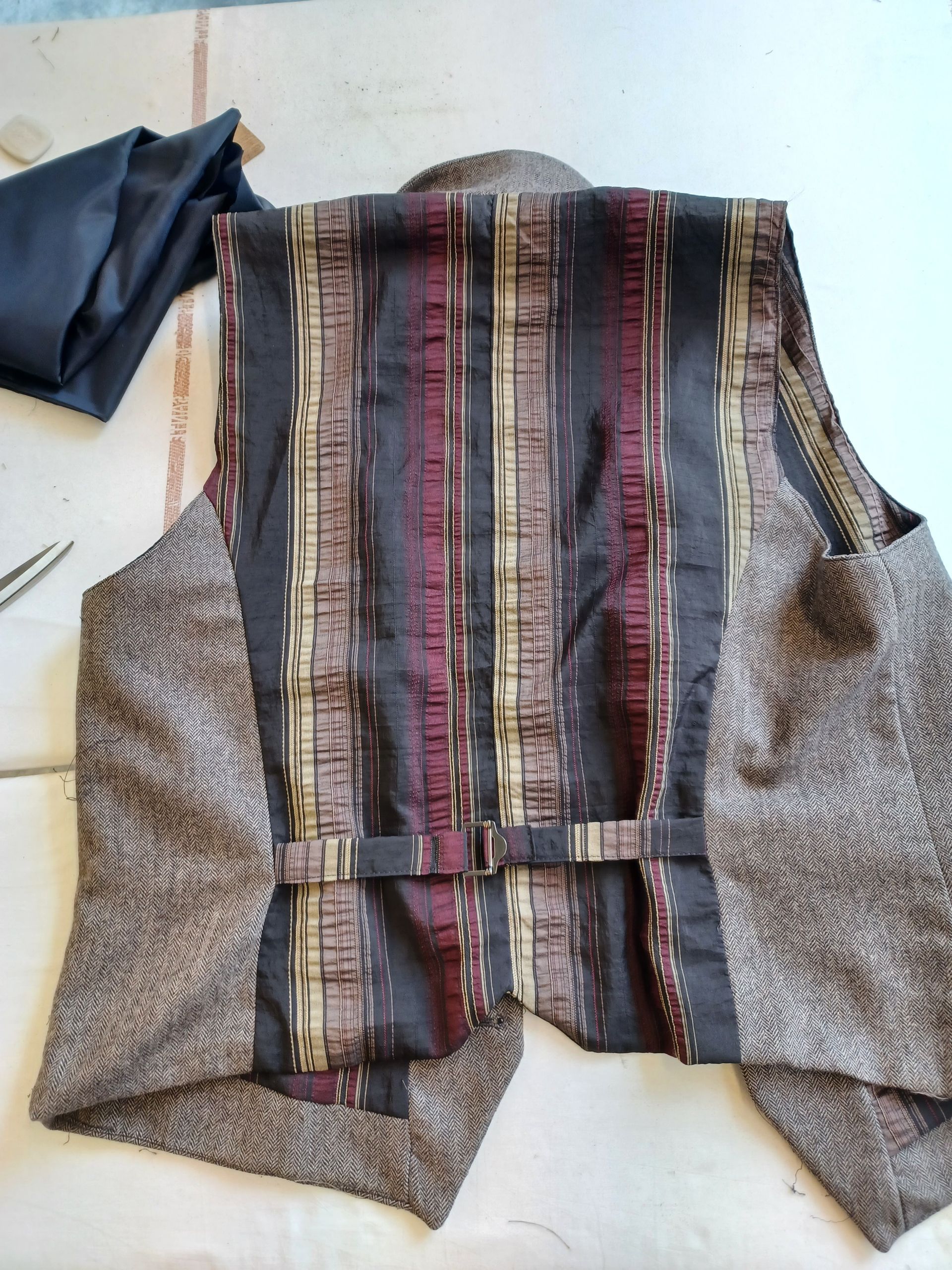 Un gilet rayé est posé sur une table à côté d'une paire de ciseaux