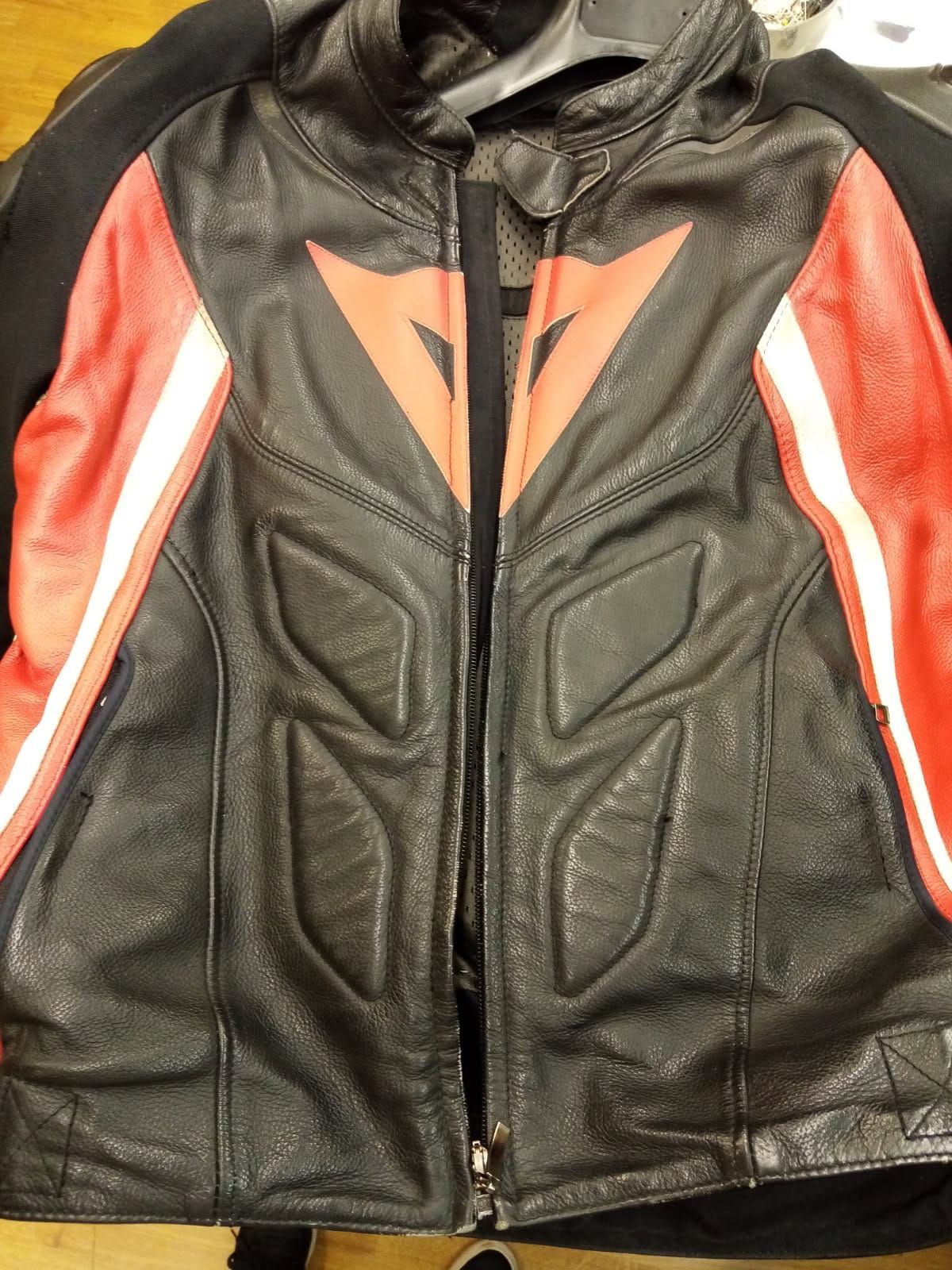 Une veste en cuir noire et rouge est accrochée à un cintre