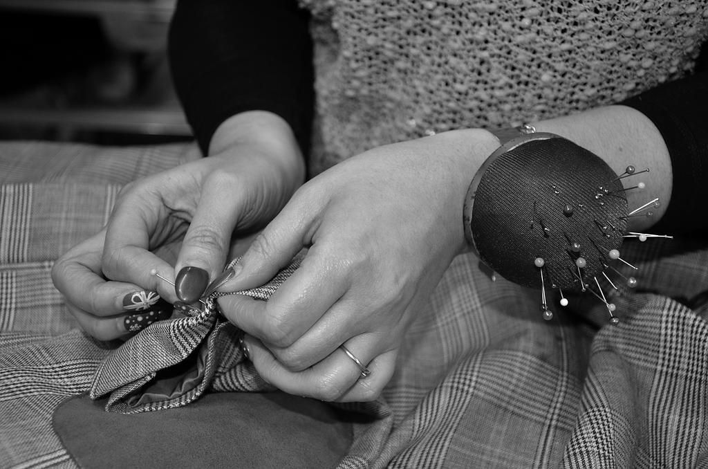 Mains d'une couturière de l'atelier Gyl Retouches épinglant un vêtement