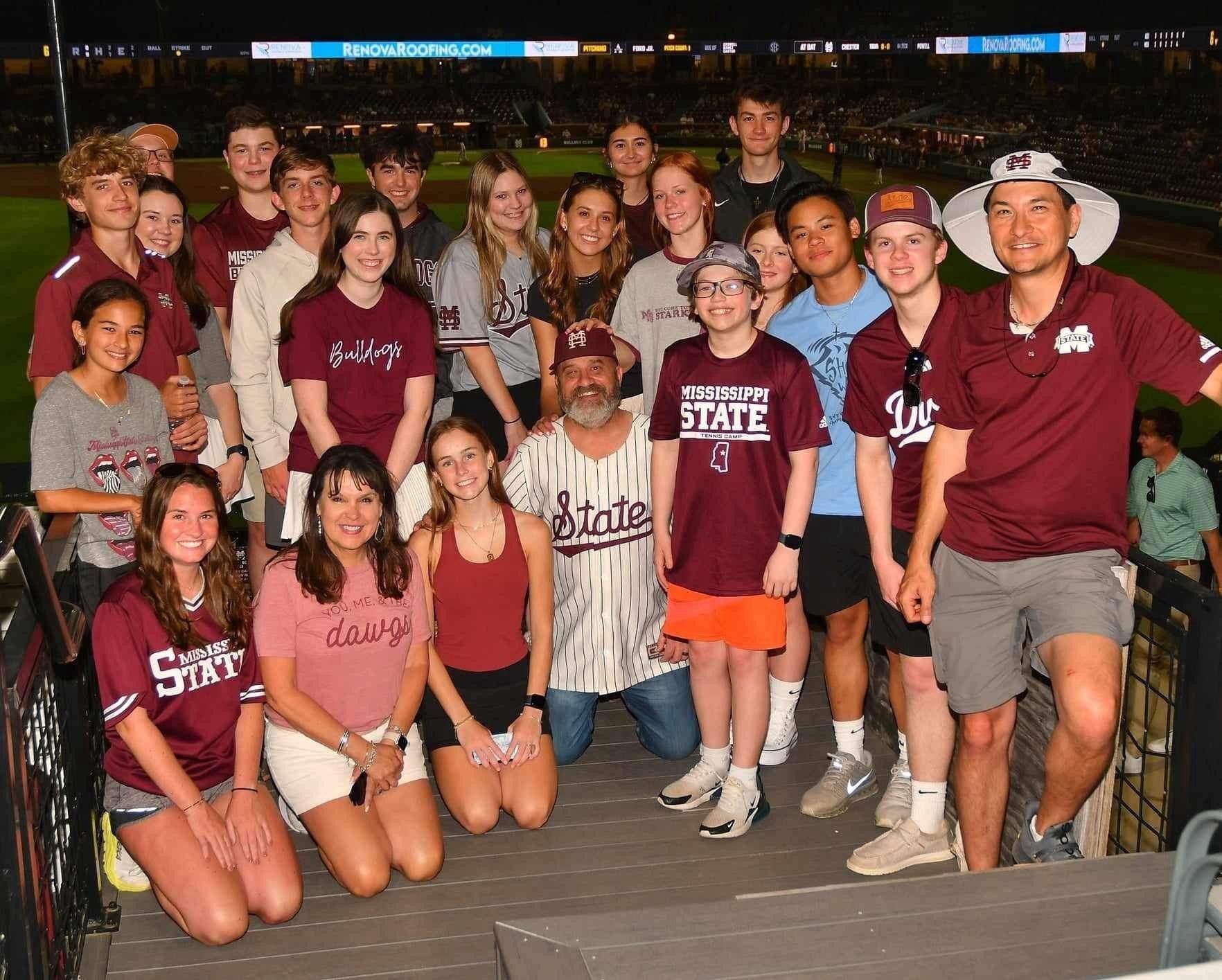 A group of people are posing for a picture on a baseball field.
