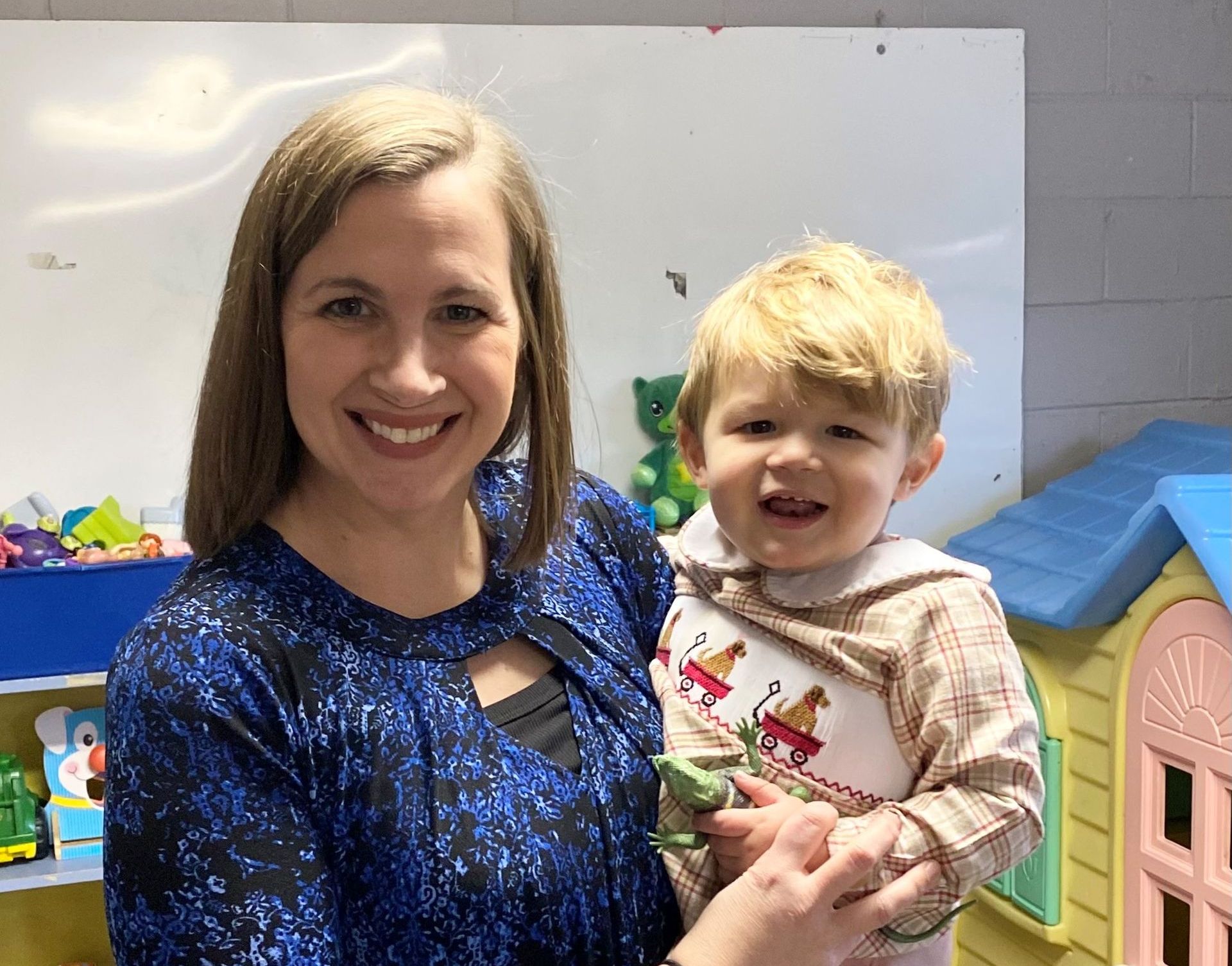 A woman is holding a baby in her arms and smiling.