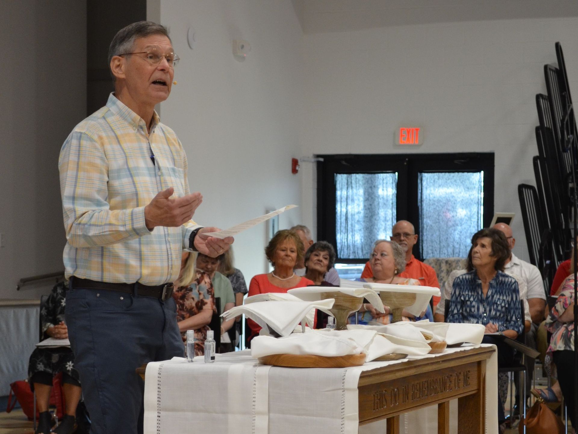 A man is standing in front of a table giving a speech to a group of people.