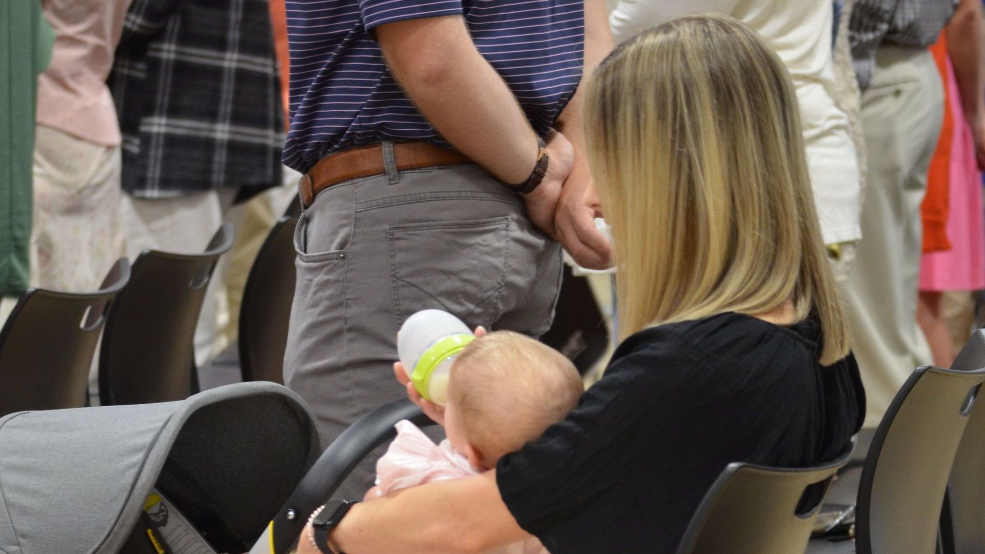 A woman is holding a baby in her arms while sitting in a chair.