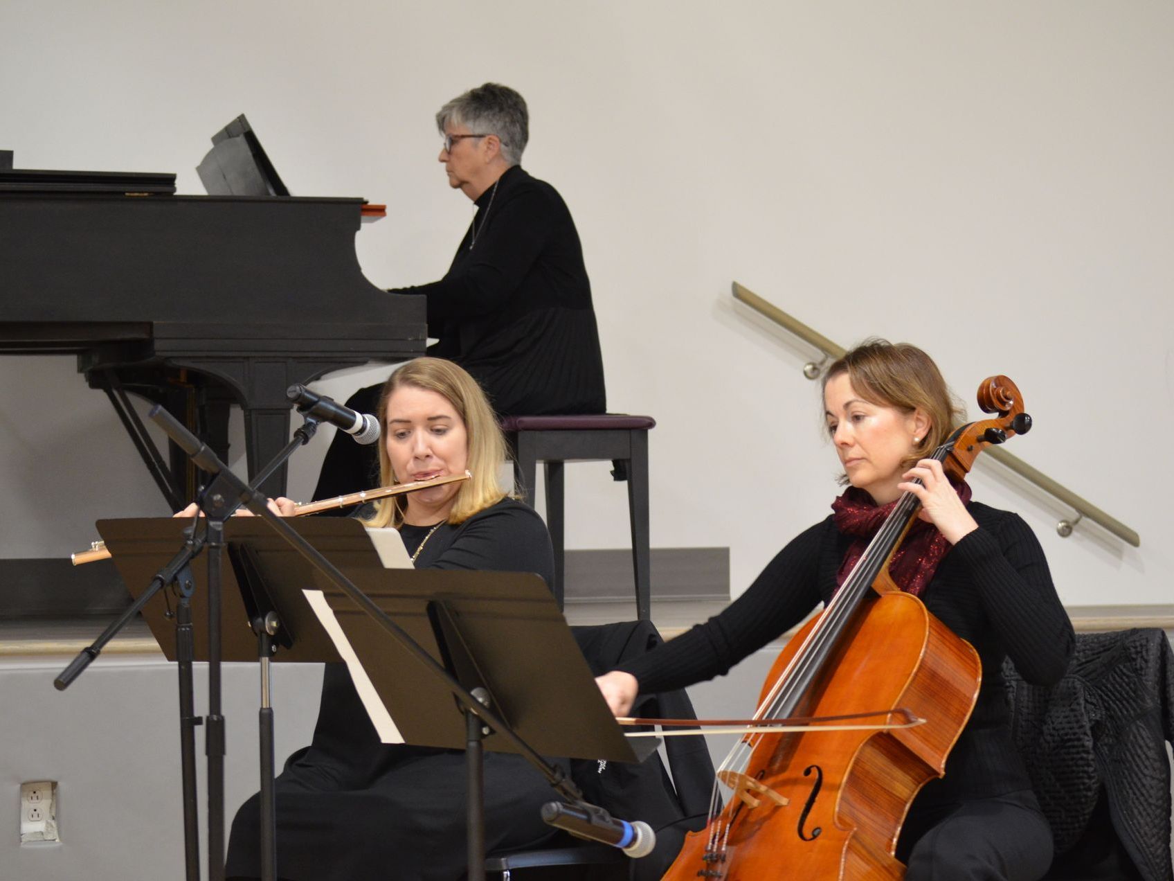 A woman is playing a flute and a woman is playing a cello