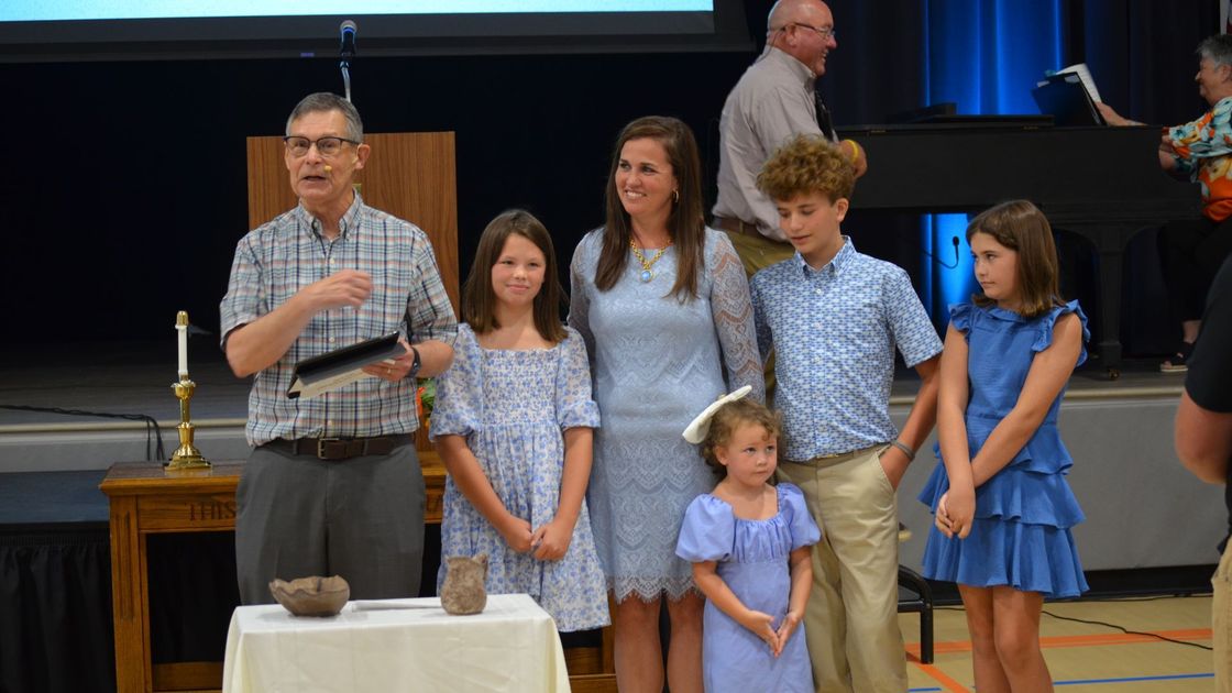 A group of people standing next to each other in front of a table.
