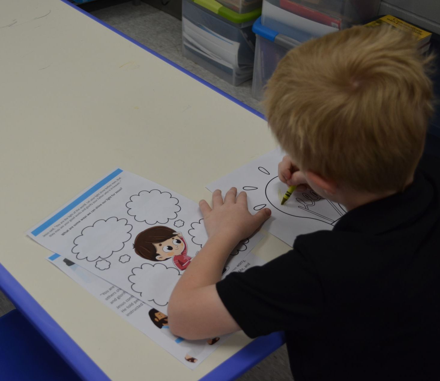 A young boy is drawing a picture of a boy with speech bubbles
