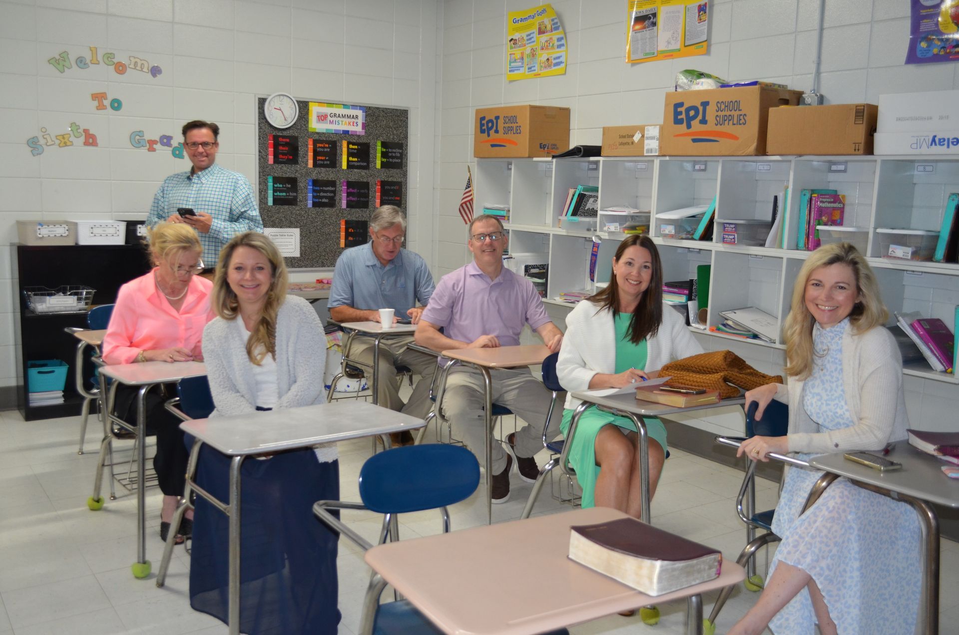 A group of people are sitting at desks in a classroom.