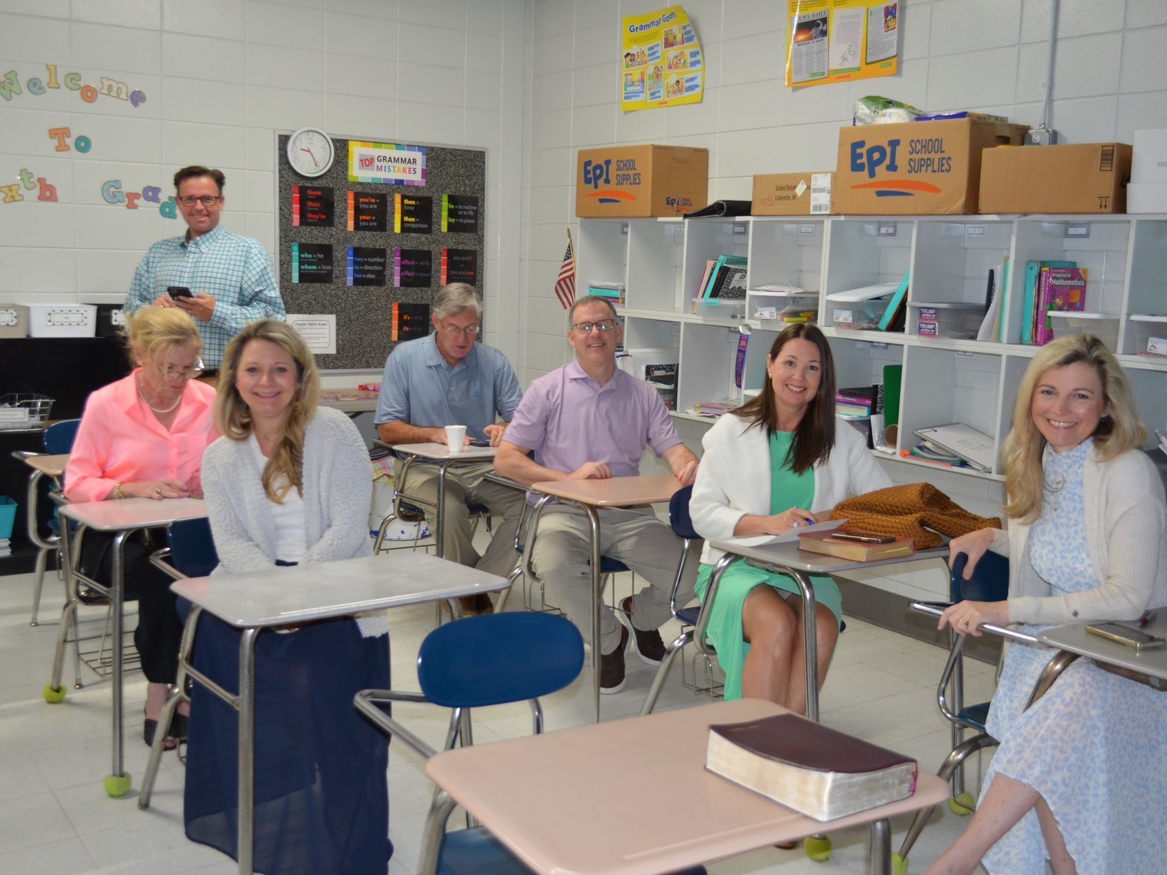 A group of people are sitting at desks in a classroom.