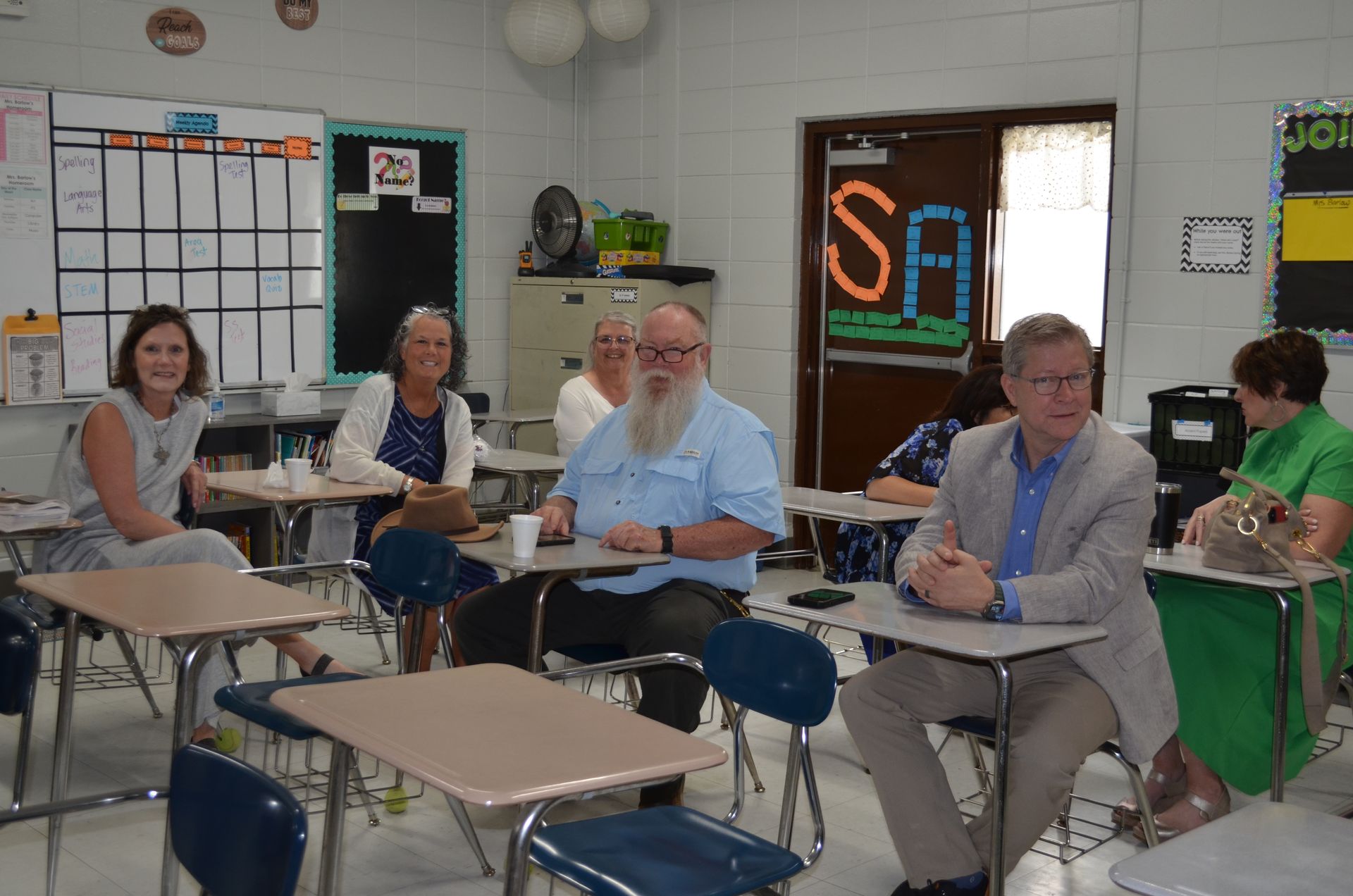 A group of people are sitting at desks in a classroom.
