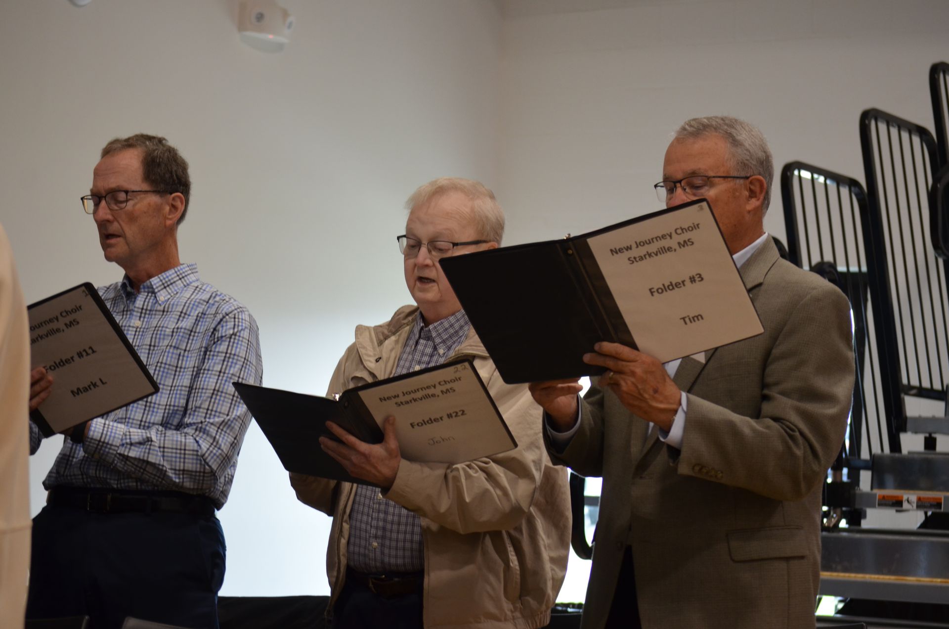 A group of men are singing in a choir while holding books.
