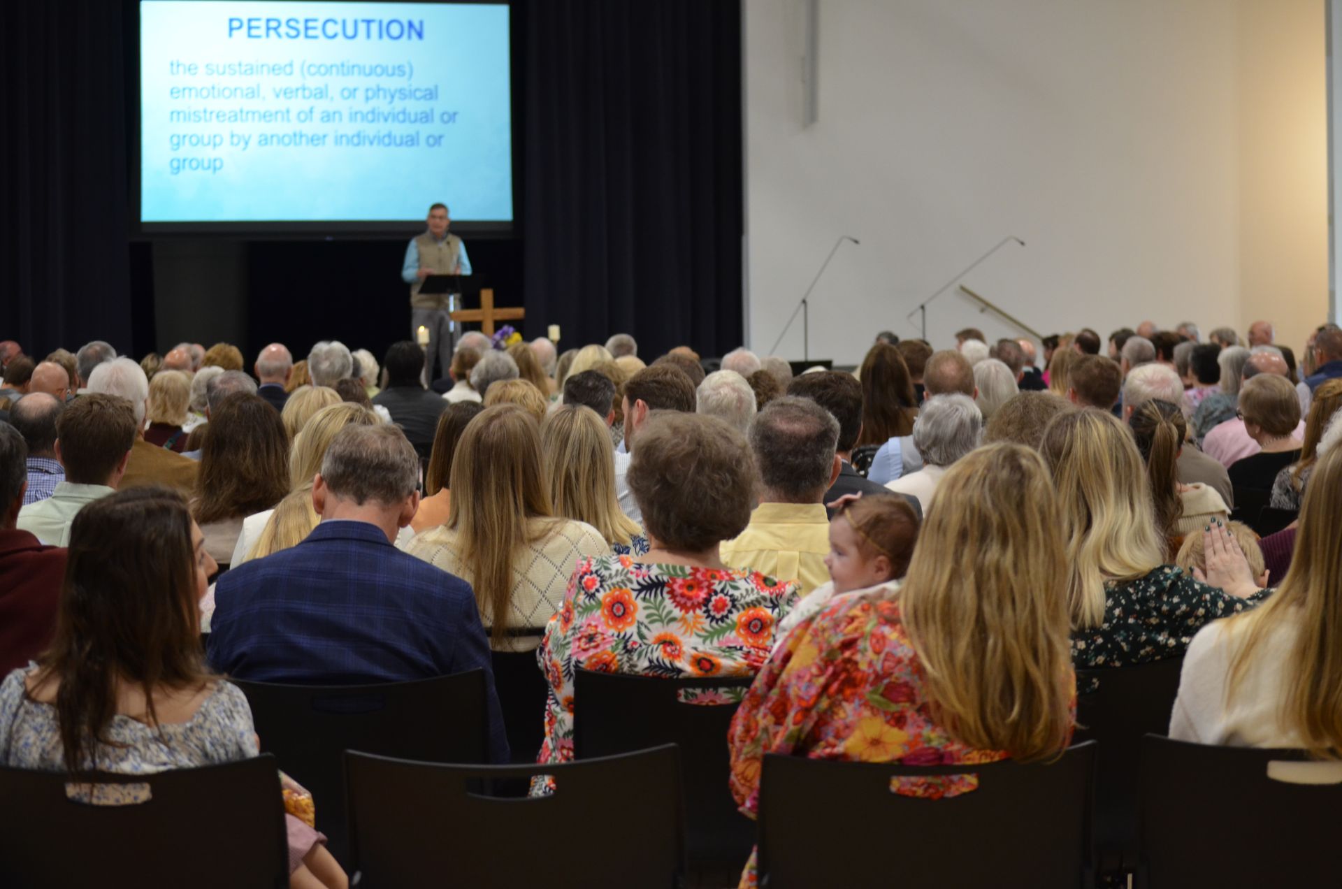 A large group of people are sitting in a room watching a presentation.
