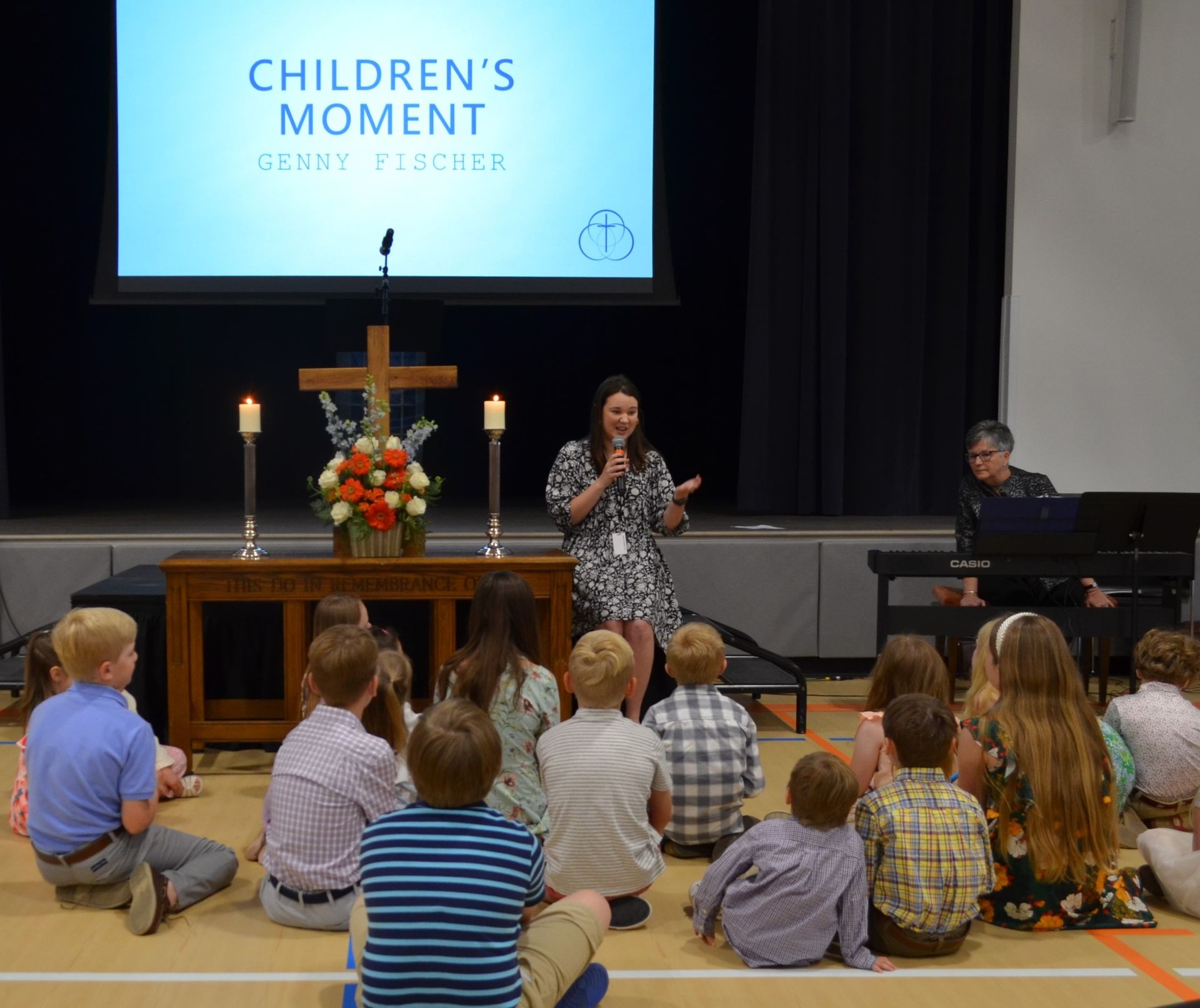 A group of children are sitting on the floor in front of a screen that says children 's moment