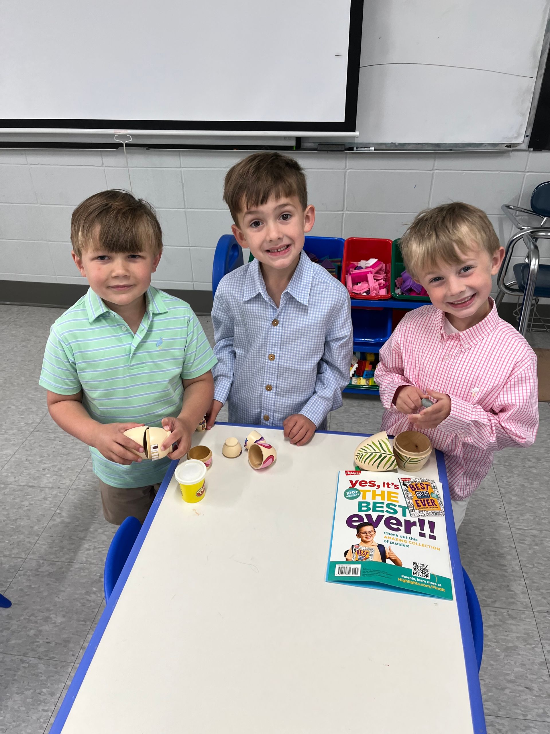 Three children are sitting at a table in a classroom.