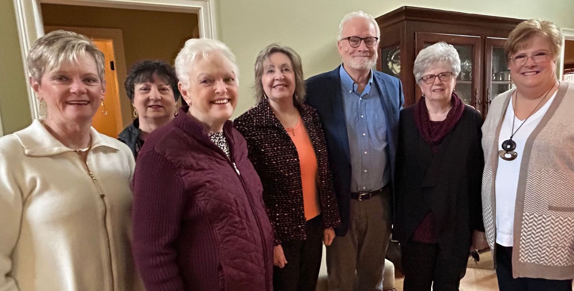 A group of older people are posing for a picture in a living room.