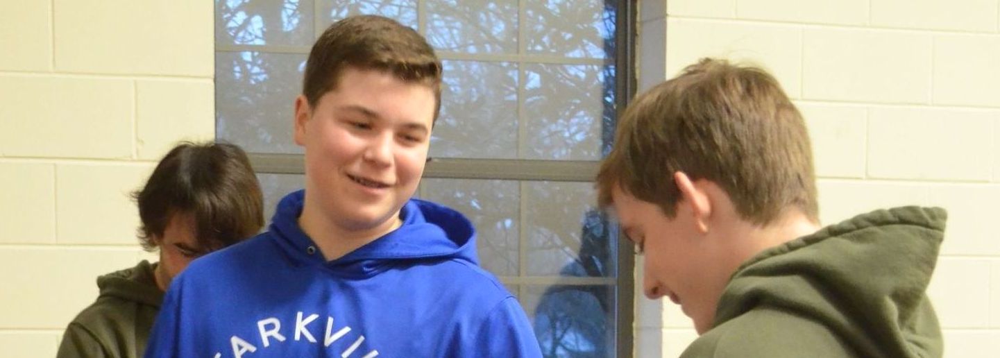 A group of young men are standing next to each other in front of a window.