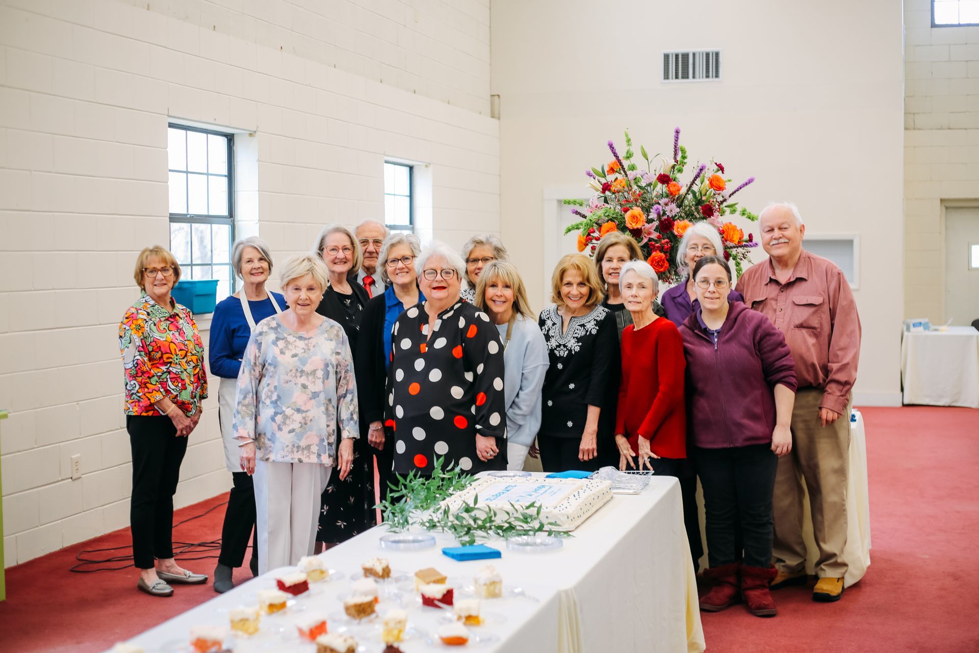 A group of people are posing for a picture in front of a table with a cake on it.