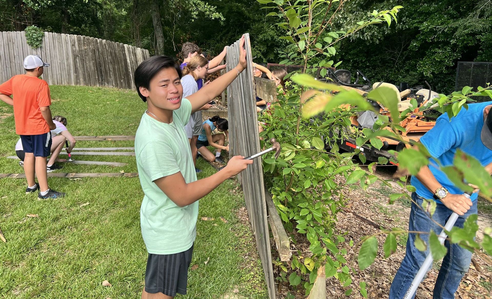 A group of people are working on a fence in a yard.
