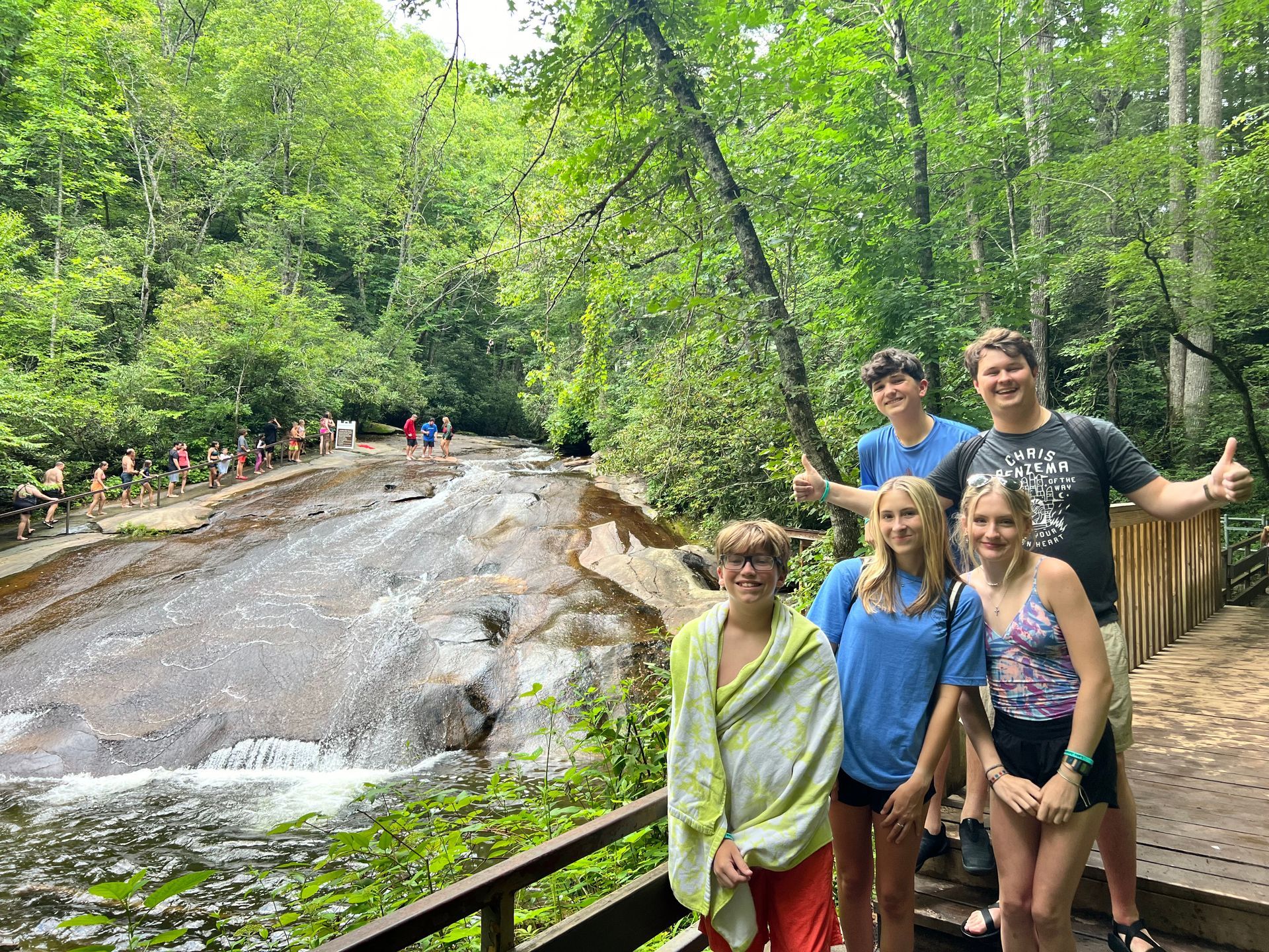 A group of people are posing for a picture in front of a waterfall.