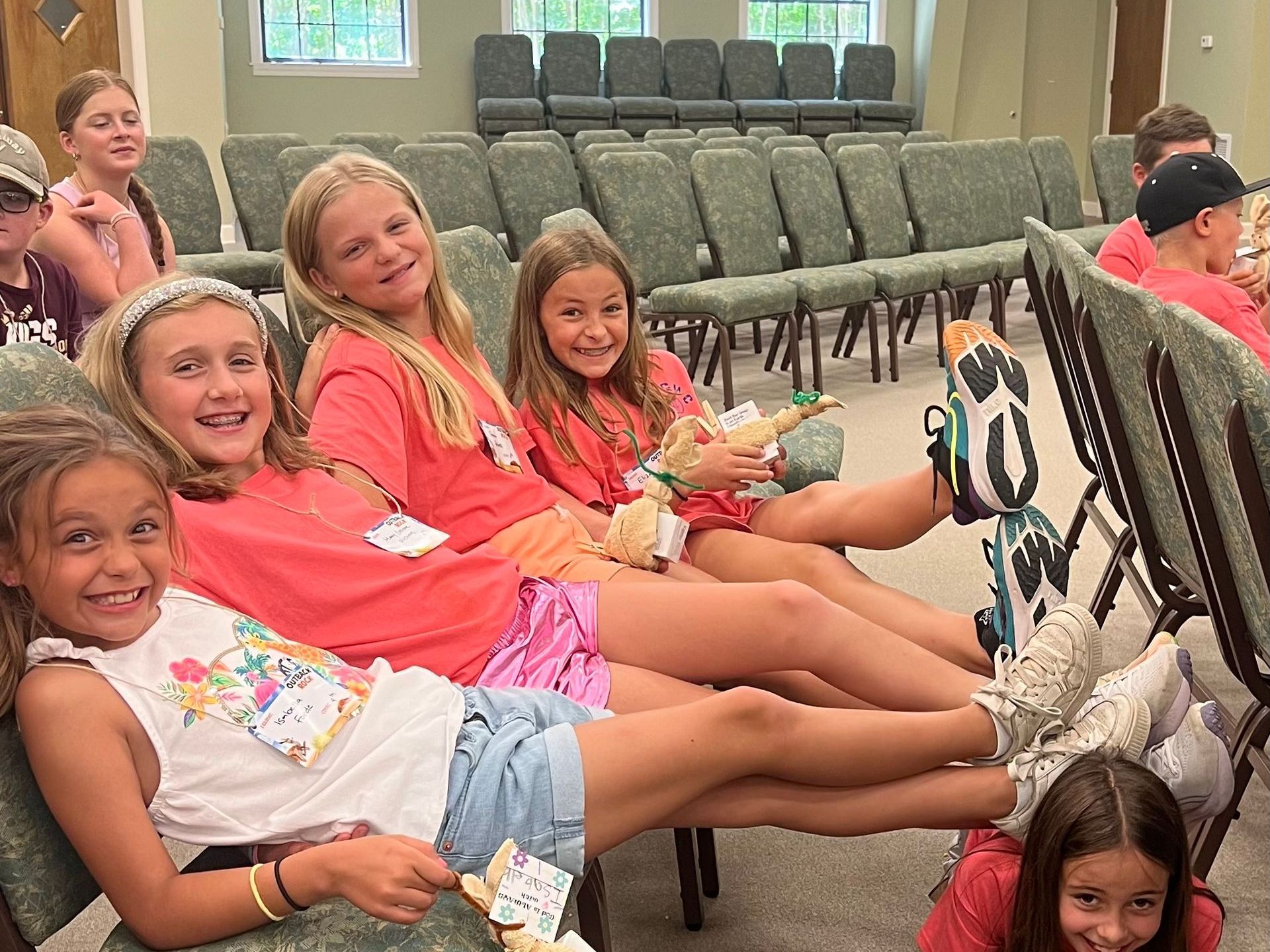 A group of young girls are sitting in chairs in a church.