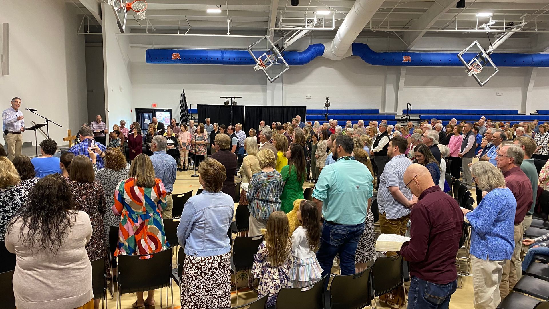 A large group of people are standing in a gym.