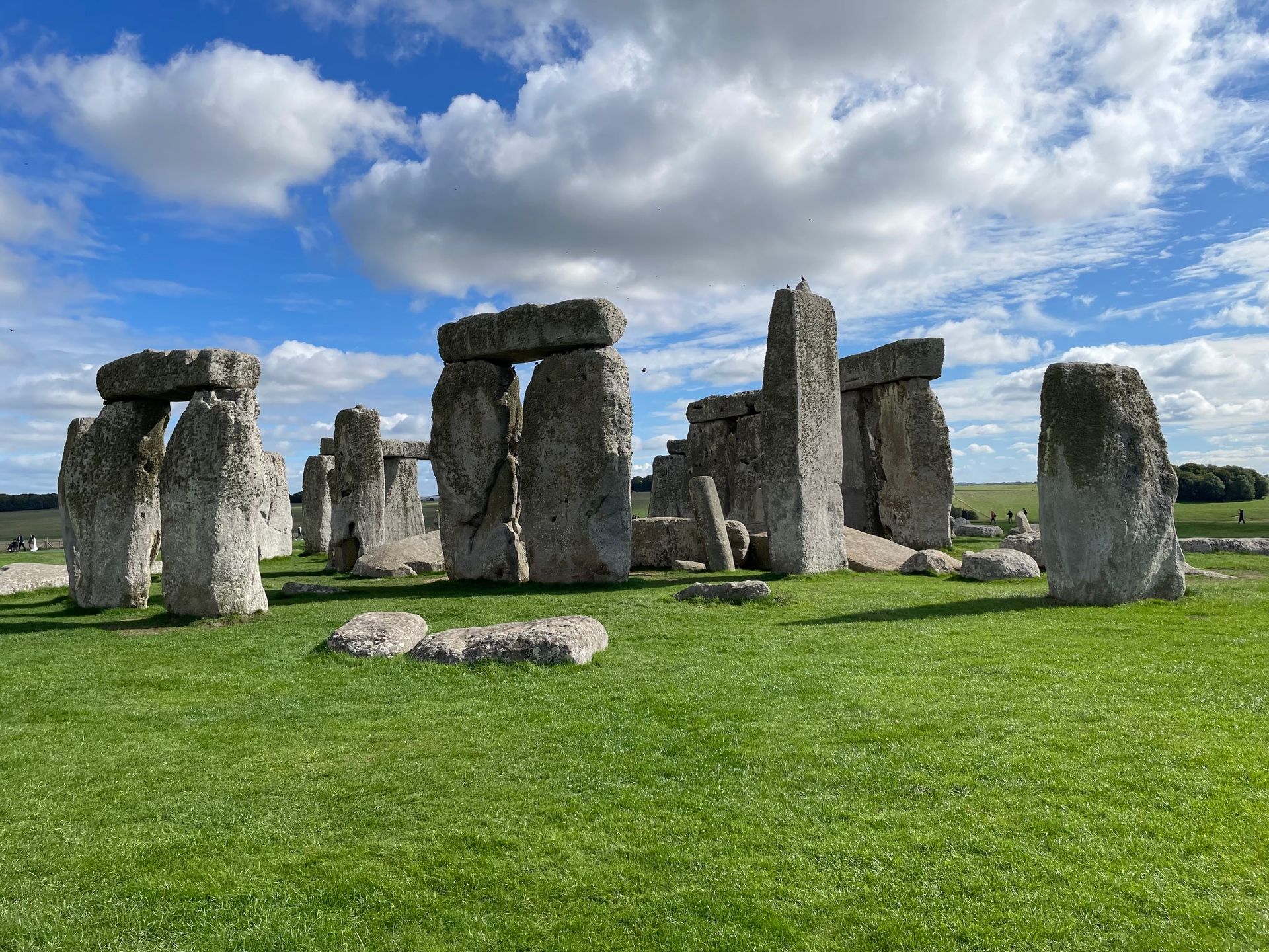 Stonehenge monument on a green field under a partly cloudy sky.