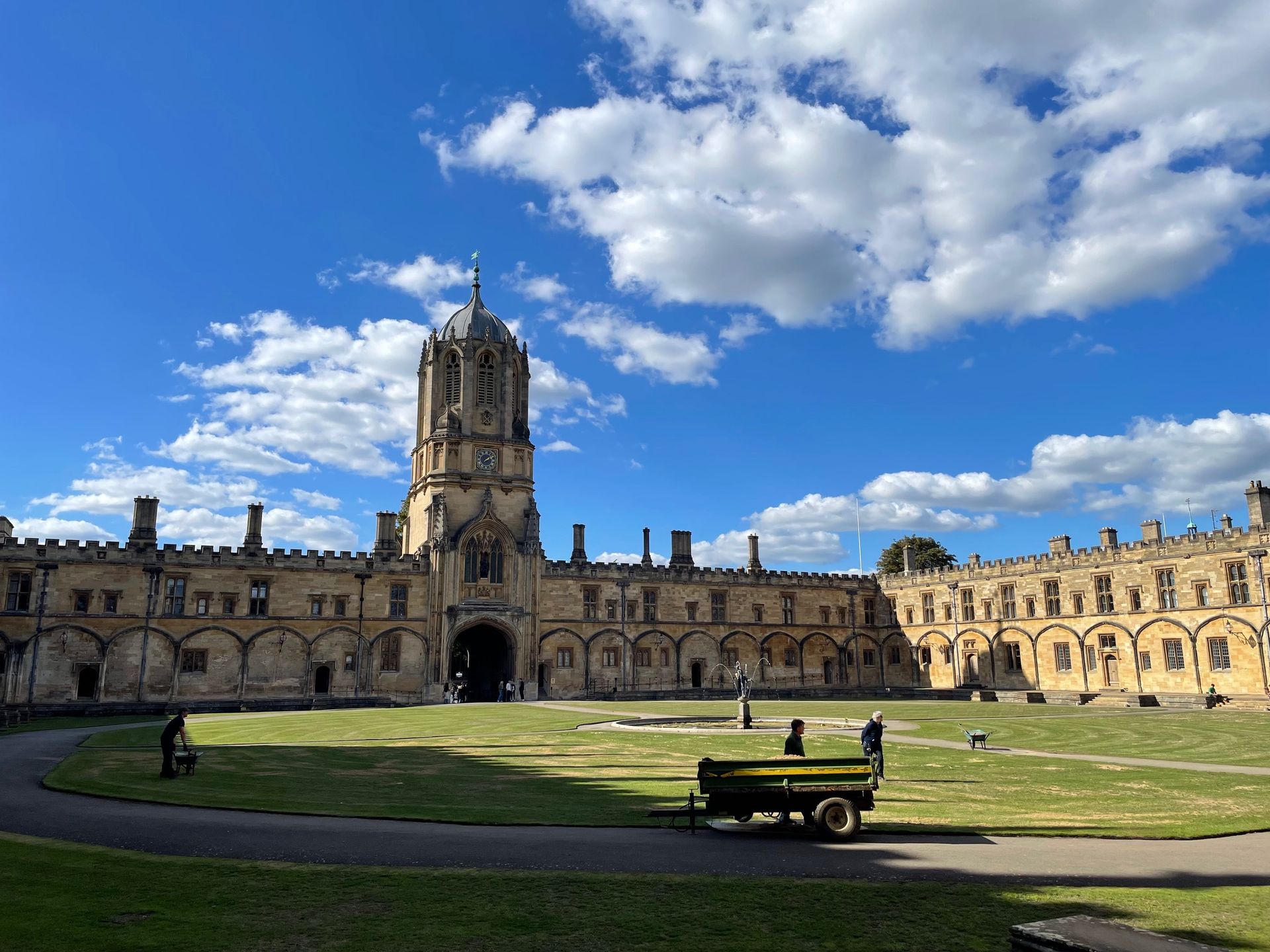 Christ Church, Oxford University, quad with clock tower under a bright blue sky with fluffy clouds.