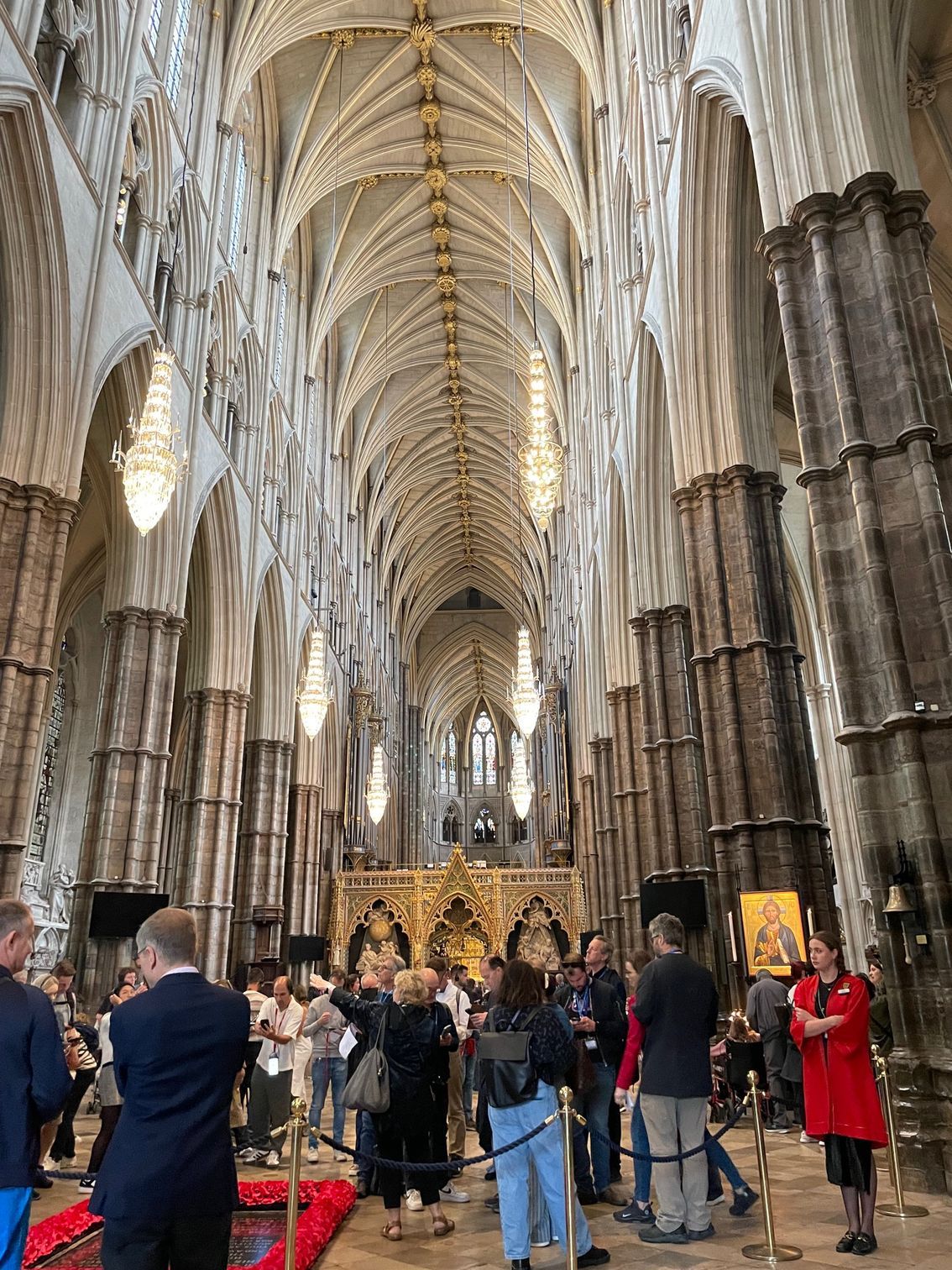 Interior of a grand cathedral with vaulted ceilings, tall columns, and a crowd of people.
