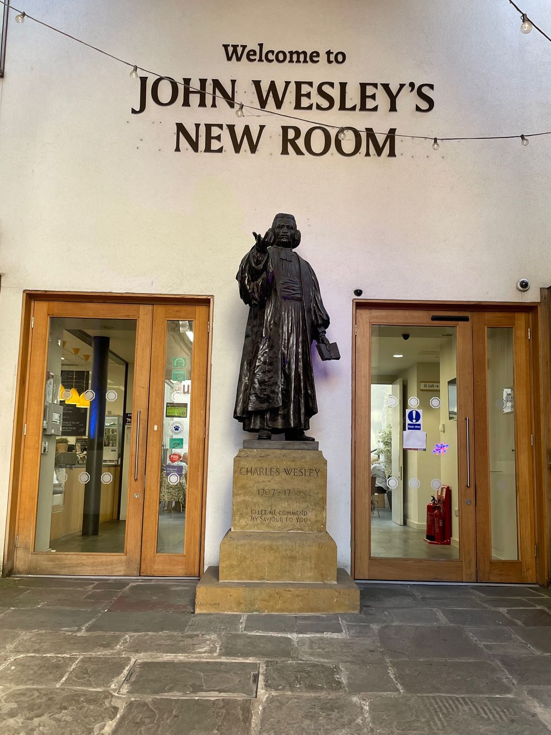 Entrance to John Wesley's New Room with statue of John Wesley and glass doors.