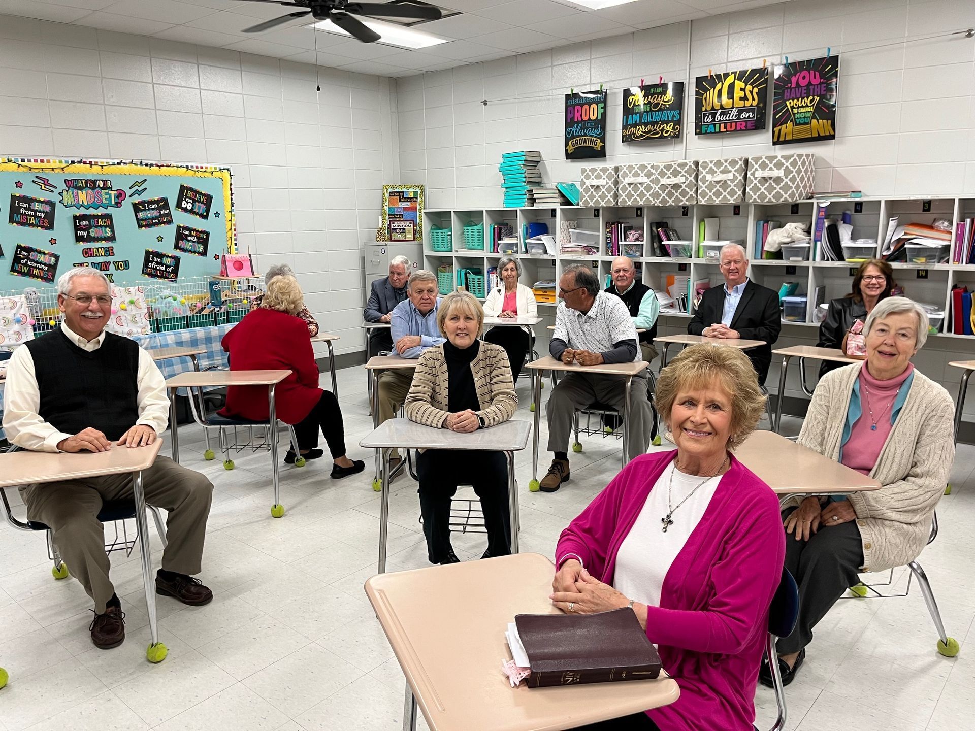 A group of people are sitting at desks in a classroom.