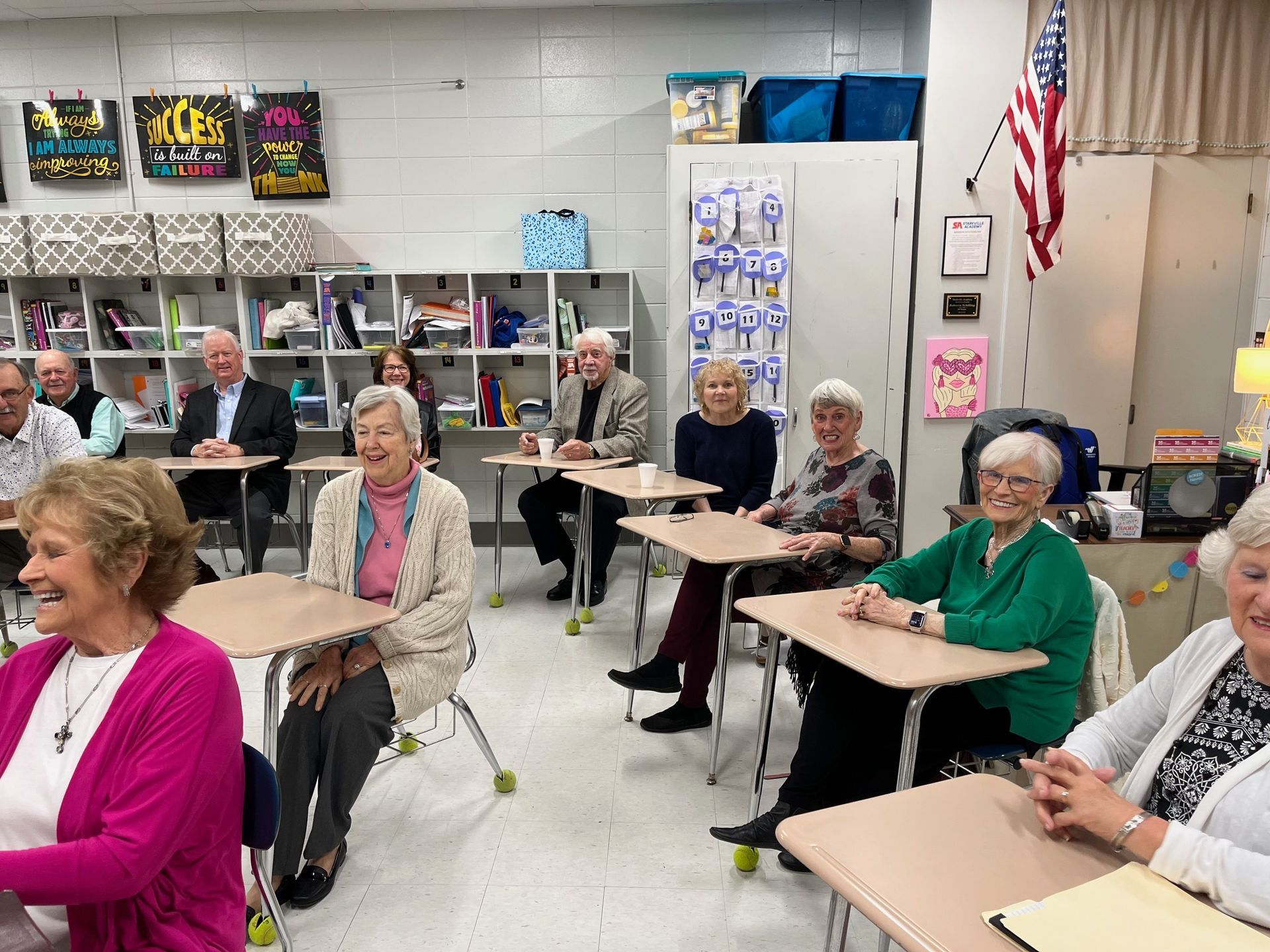 A group of older people are sitting at desks in a classroom.
