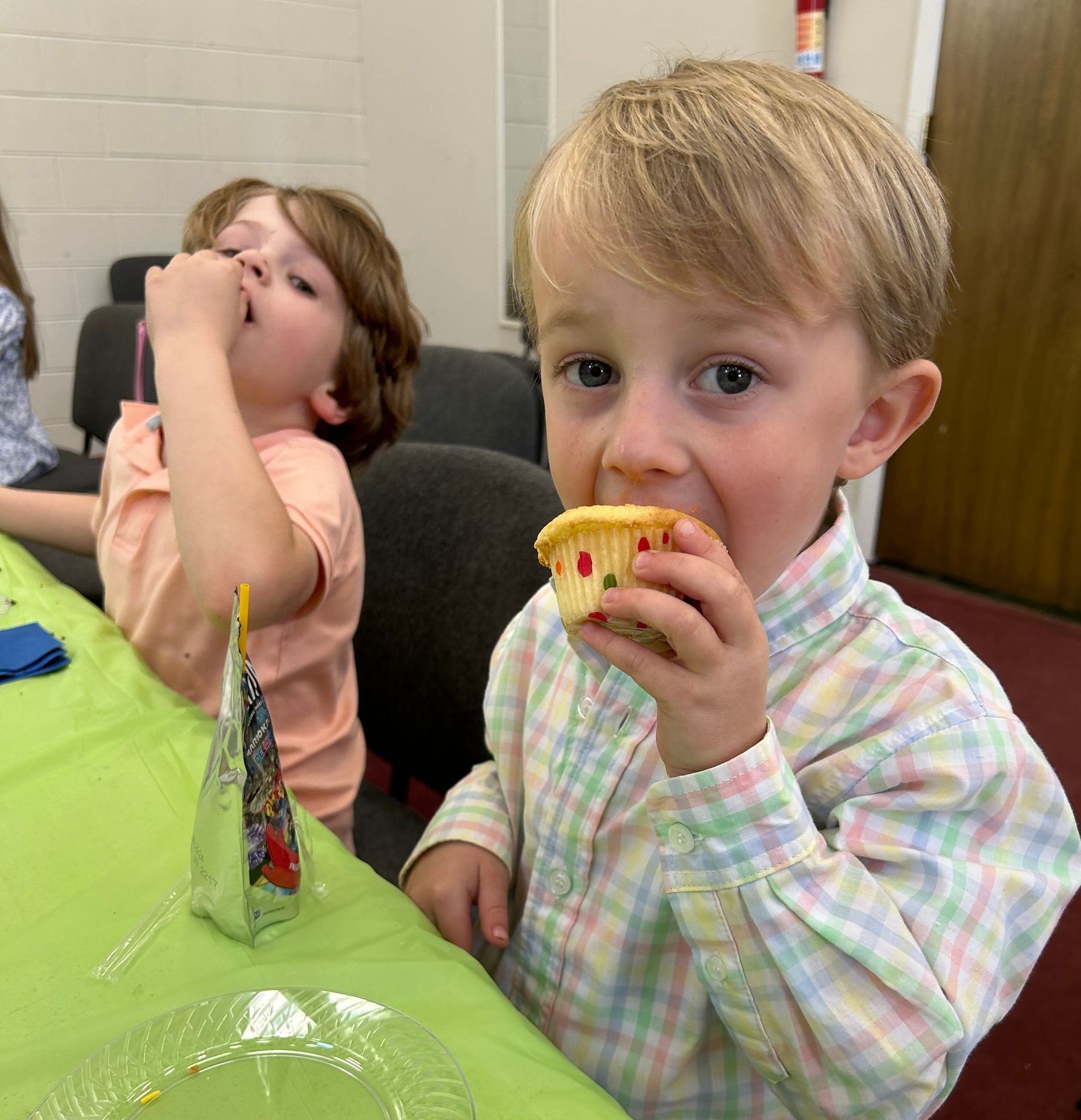 A little boy is eating a cupcake at a table