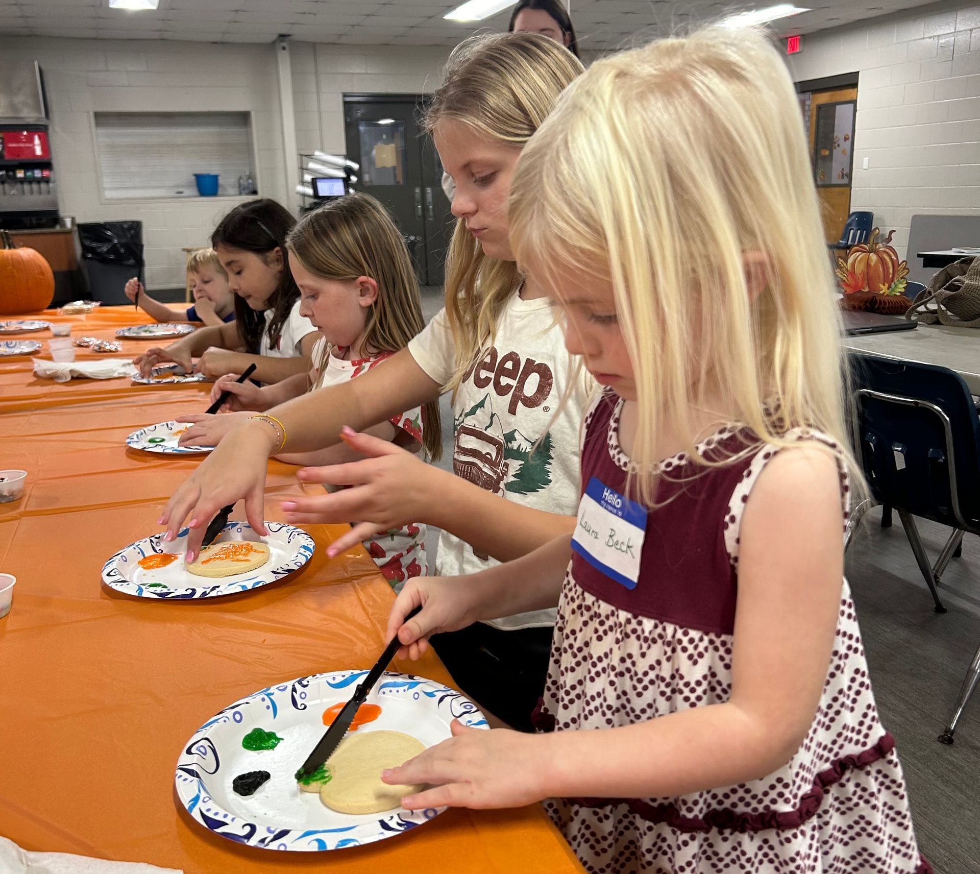 A group of young girls are sitting at a table with plates of food.