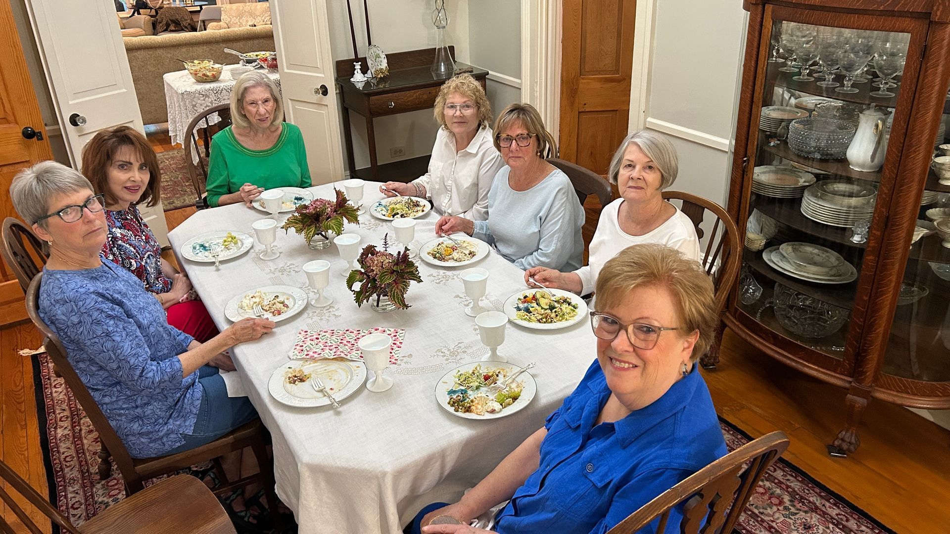 A group of women seated around a dining table set for a meal.