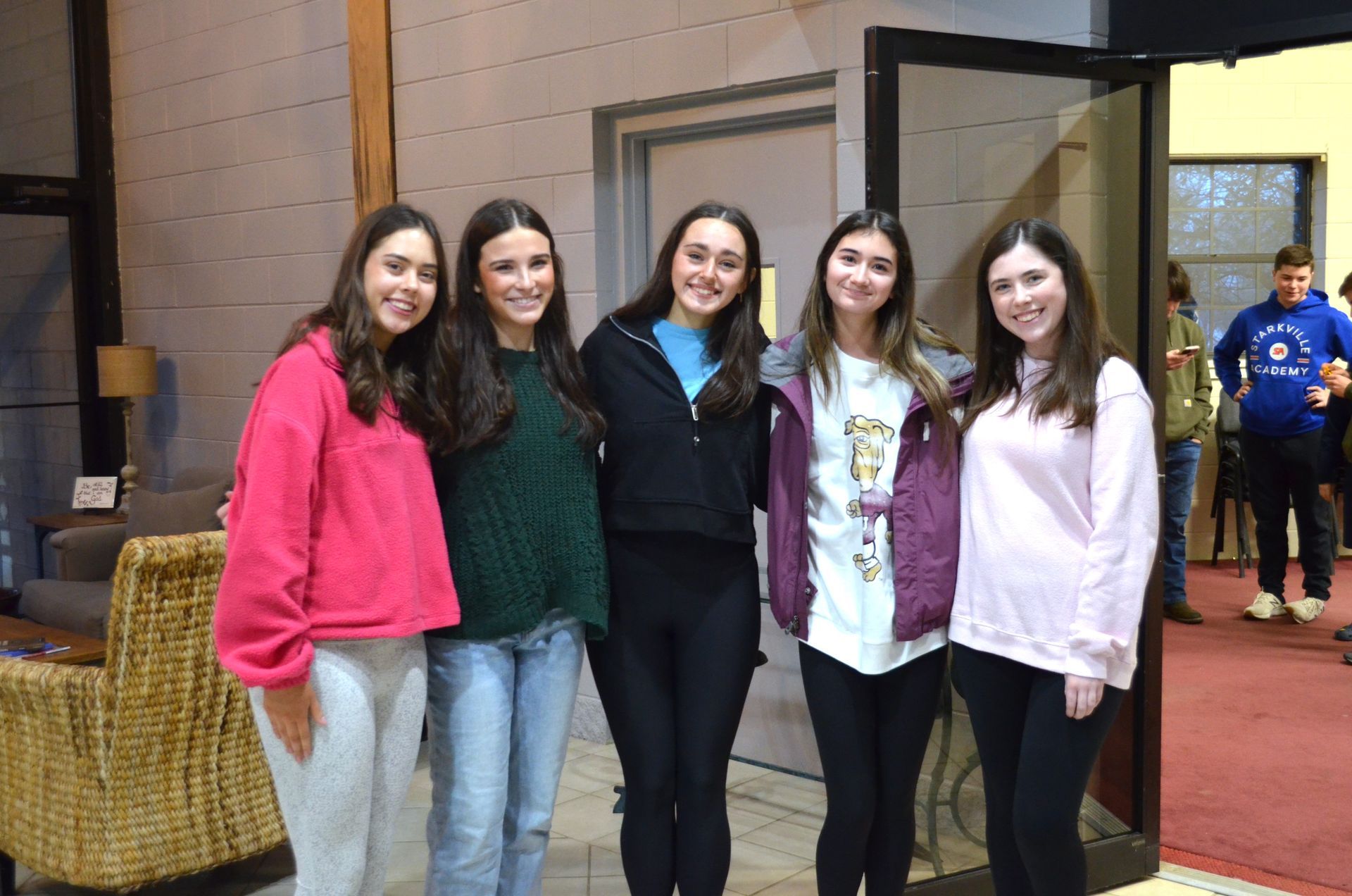 A group of young women are posing for a picture in a room.