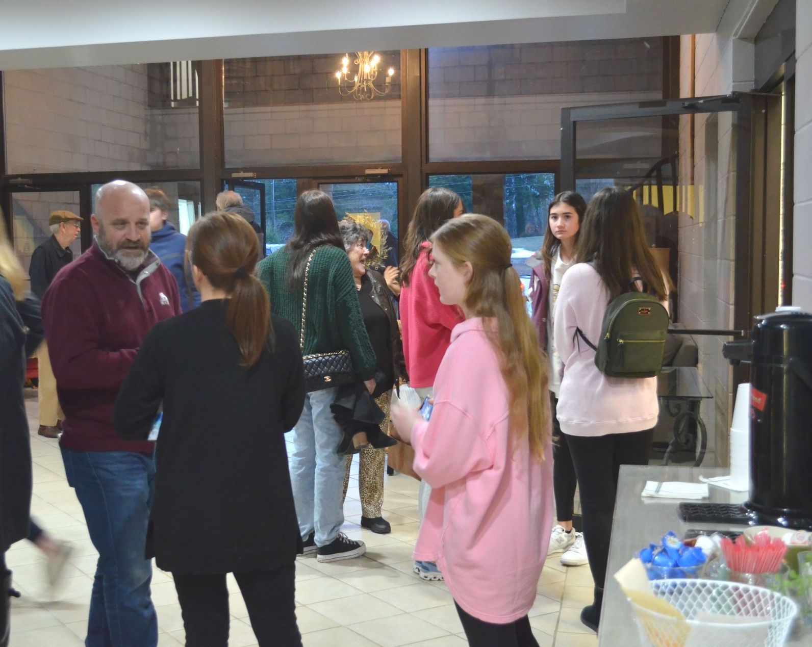 A group of people are standing in a room talking to each other.