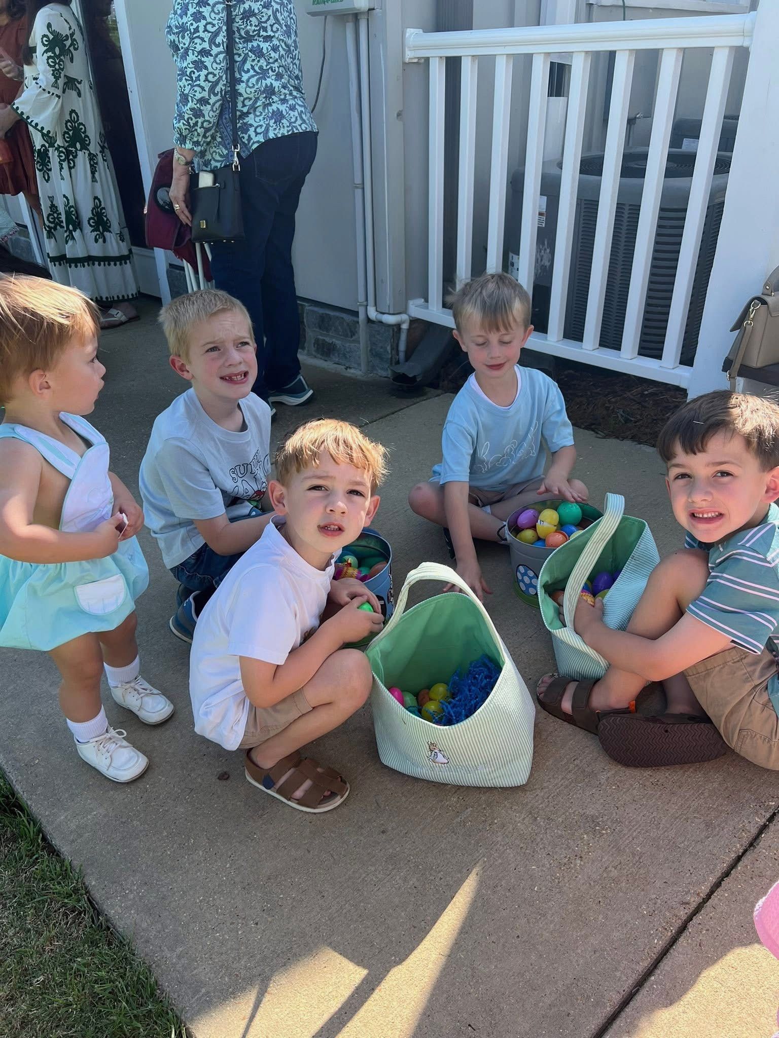 A group of children are sitting on the ground playing with easter eggs.