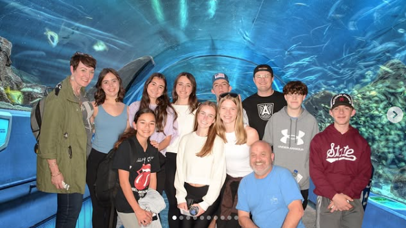 A group of people are posing for a picture in front of an aquarium.