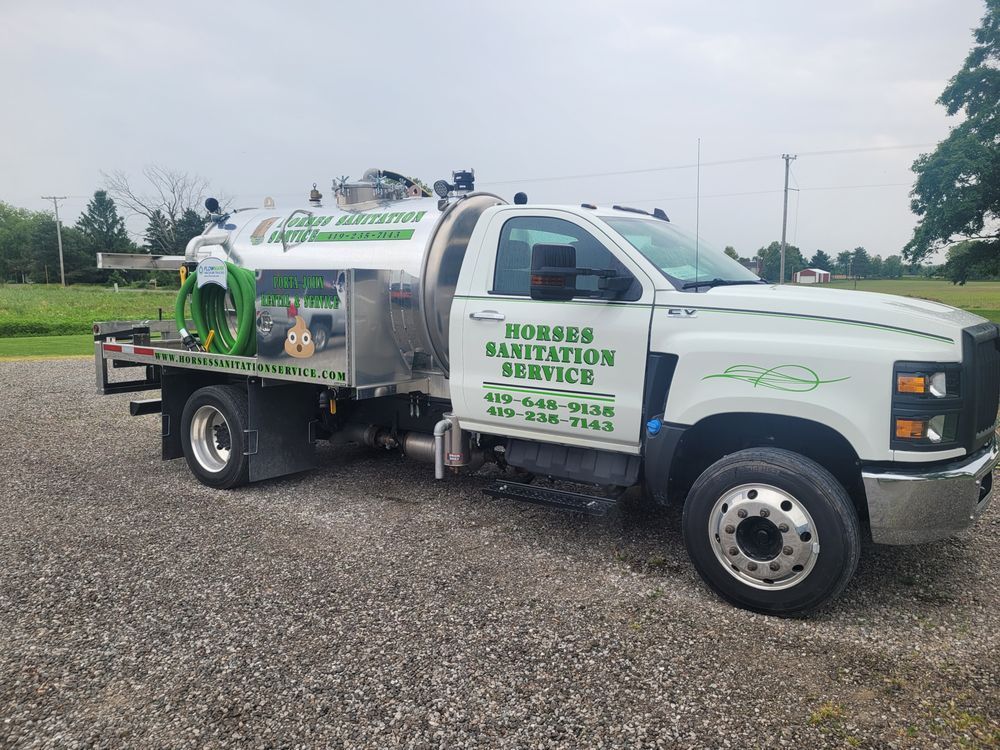 A white Horses Sanitation Service tanker truck parked on a gravel lot under a cloudy sky.