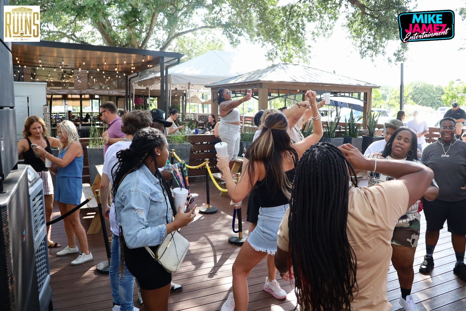 People dancing and socializing at an outdoor patio event with drinks and a lively crowd